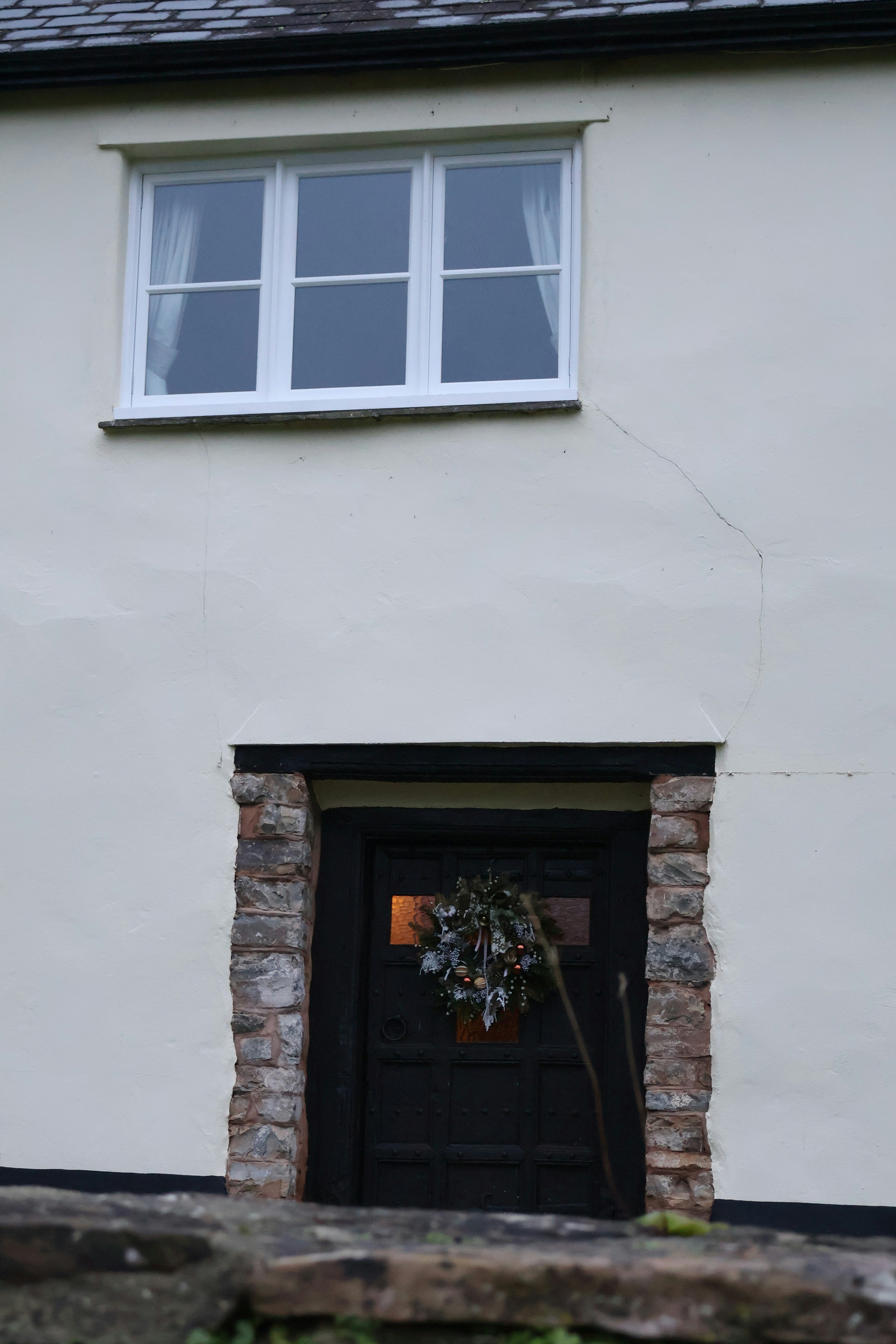 Eine rustikale Tür mit einem Kranz und einem Fenster darüber.