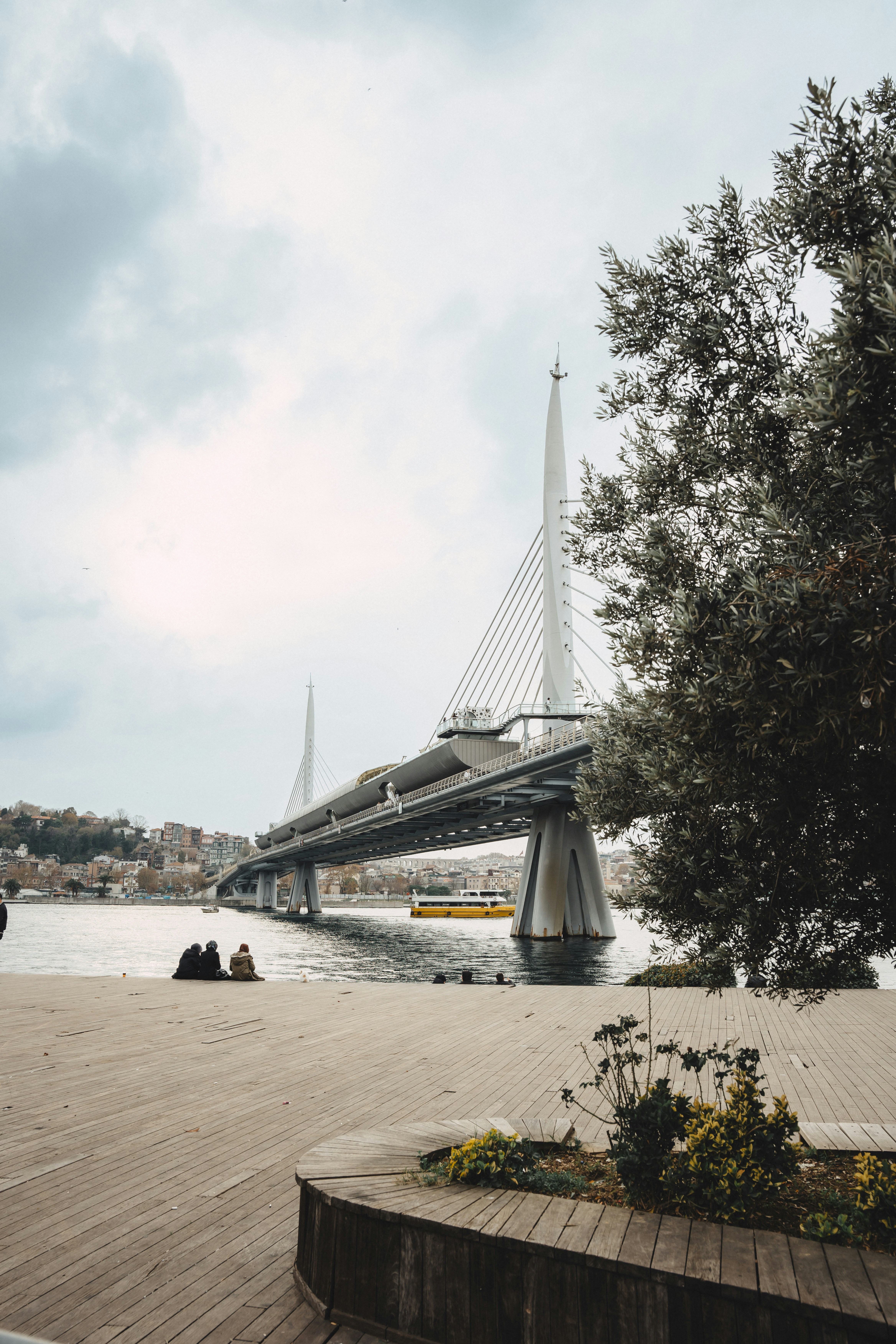Gente sentada junto a un puente moderno sobre el agua