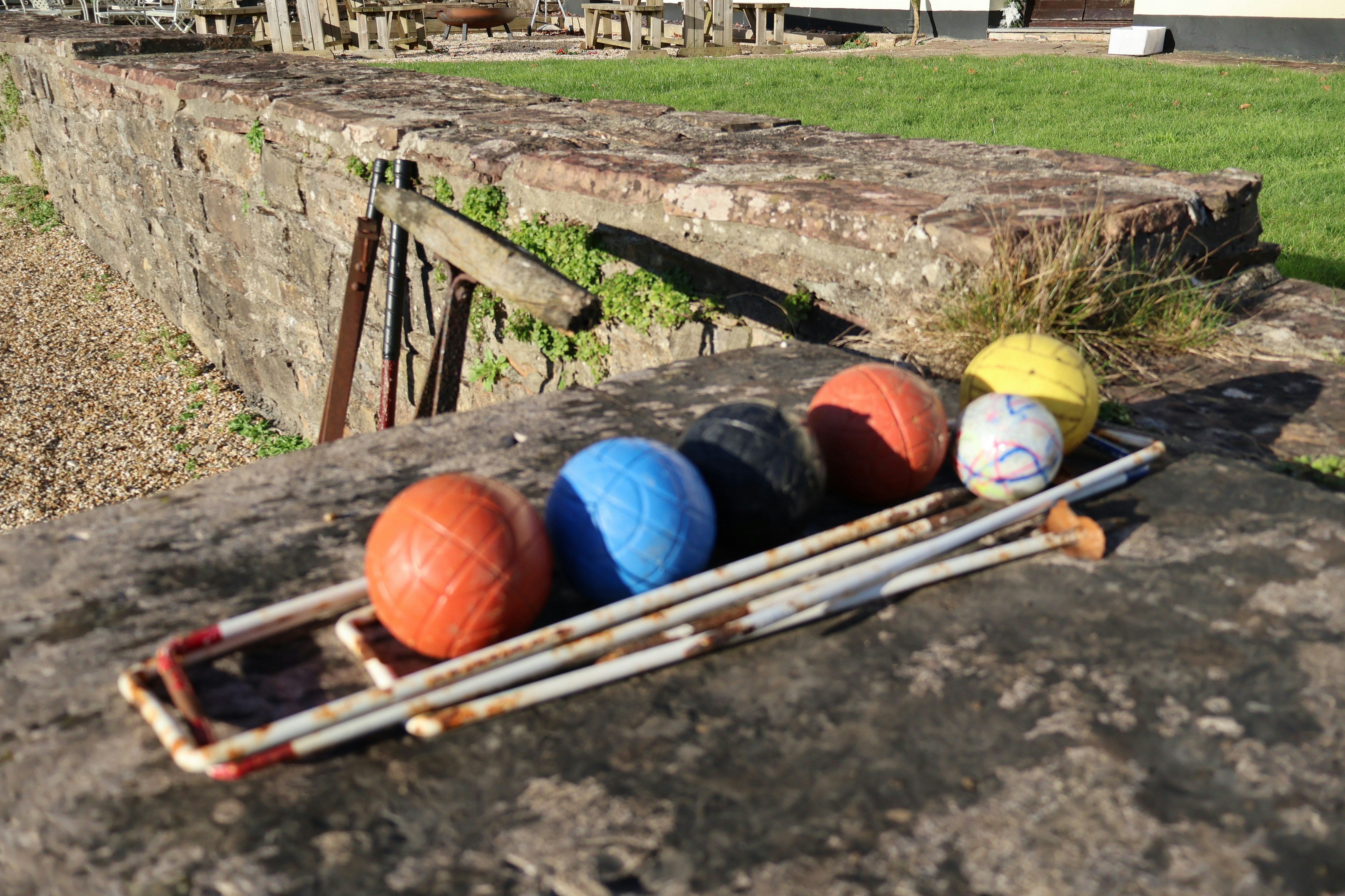Croquet set with balls and mallets on stone wall