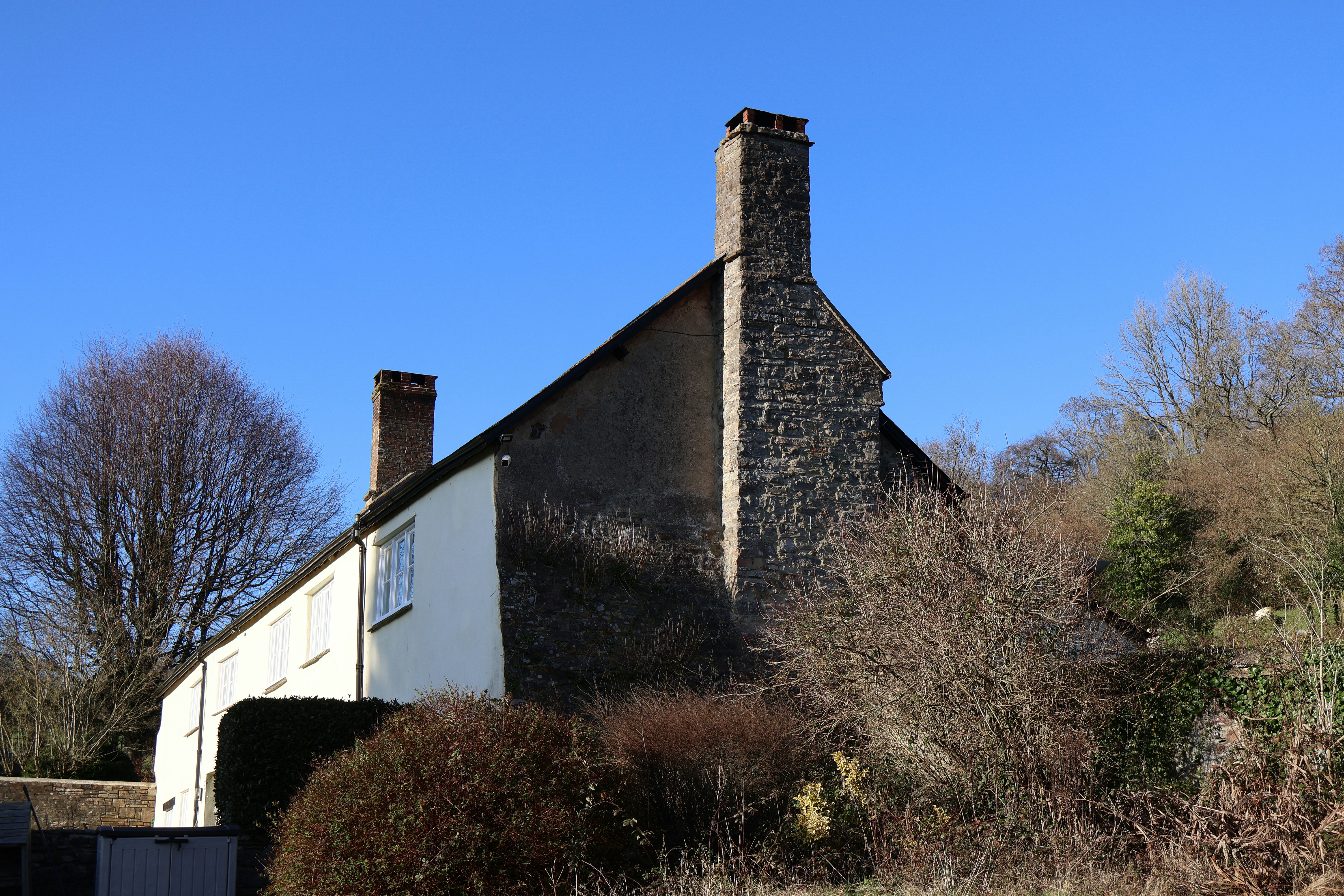A white cottage with stone accents under blue sky.
