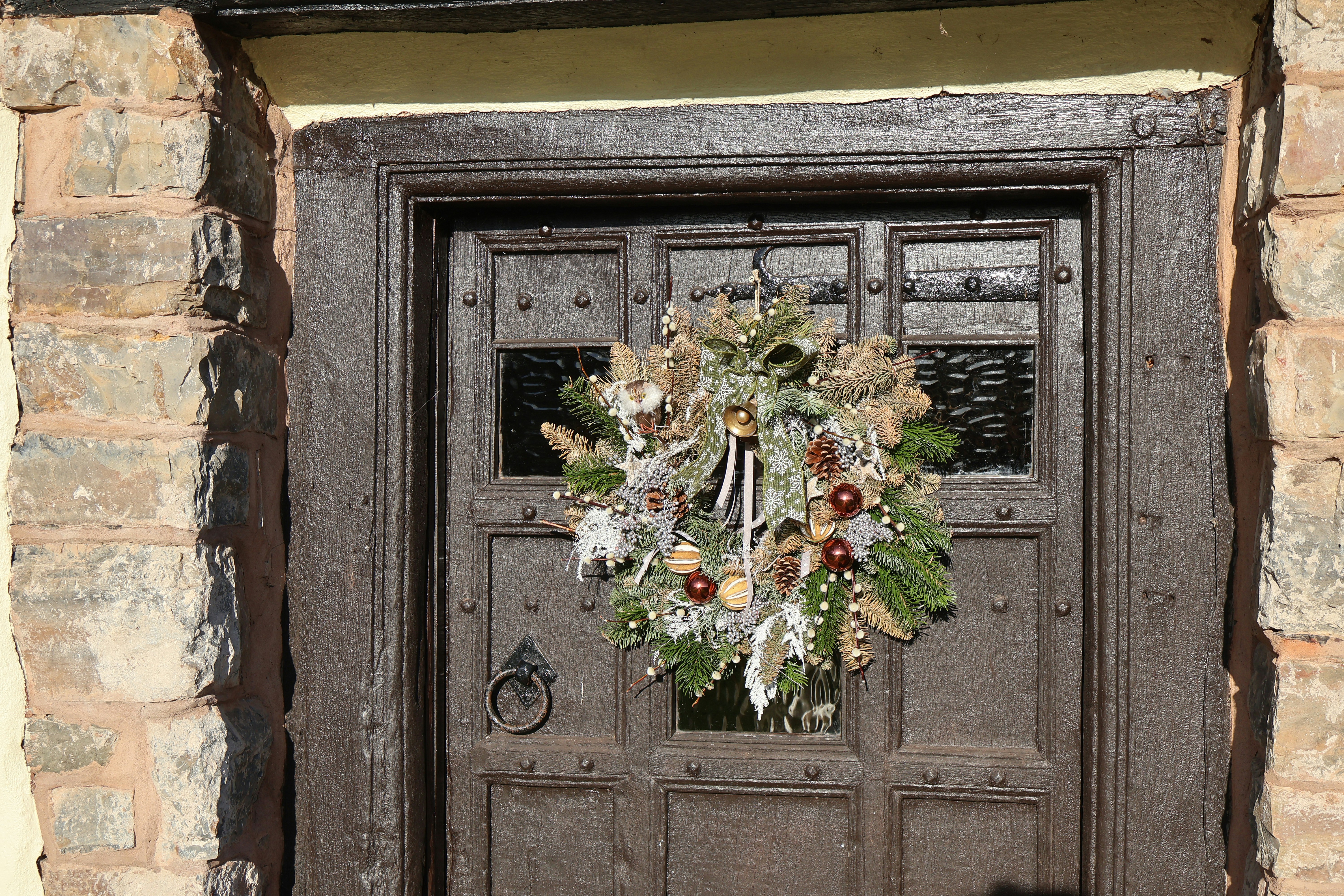 A festive wreath hangs on a rustic wooden door.