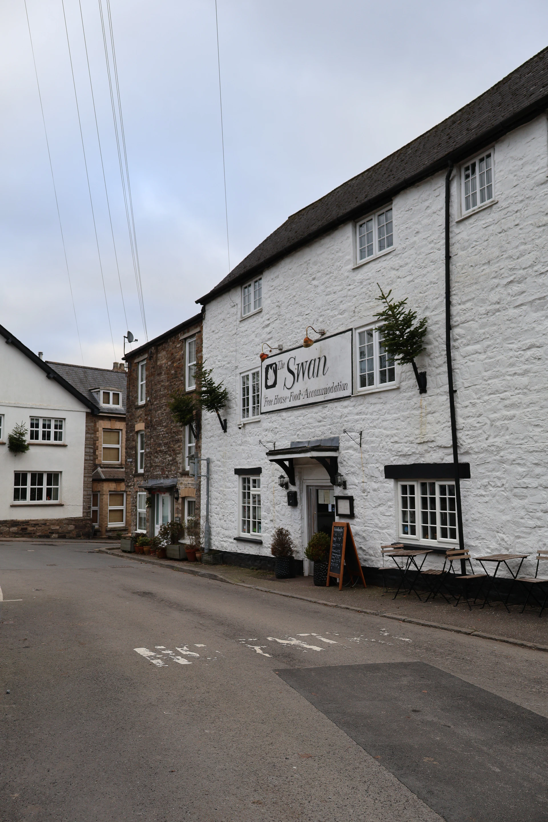 White building with "the swan" sign on street.