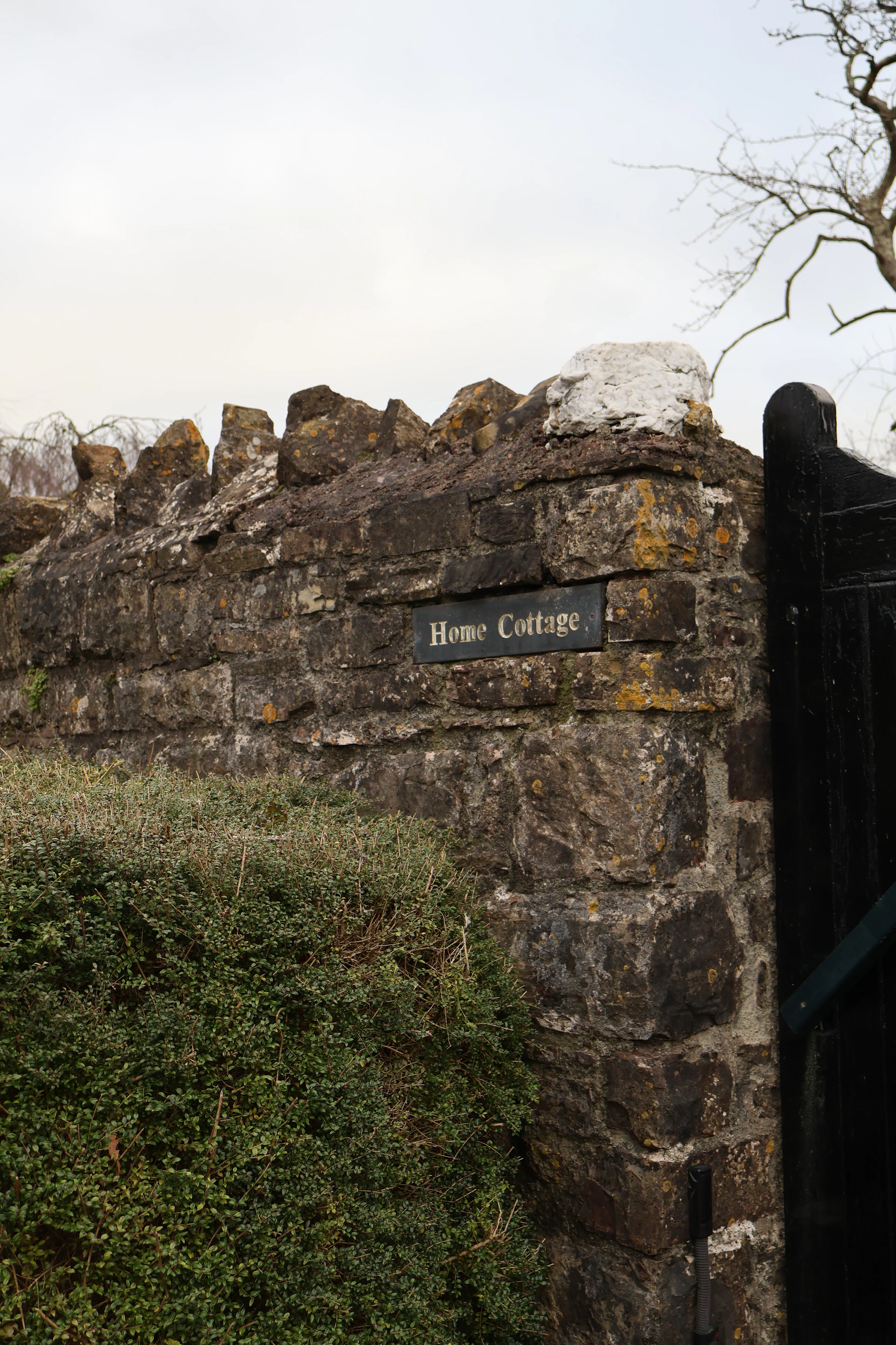 Stone wall with "home cottage" sign and gate