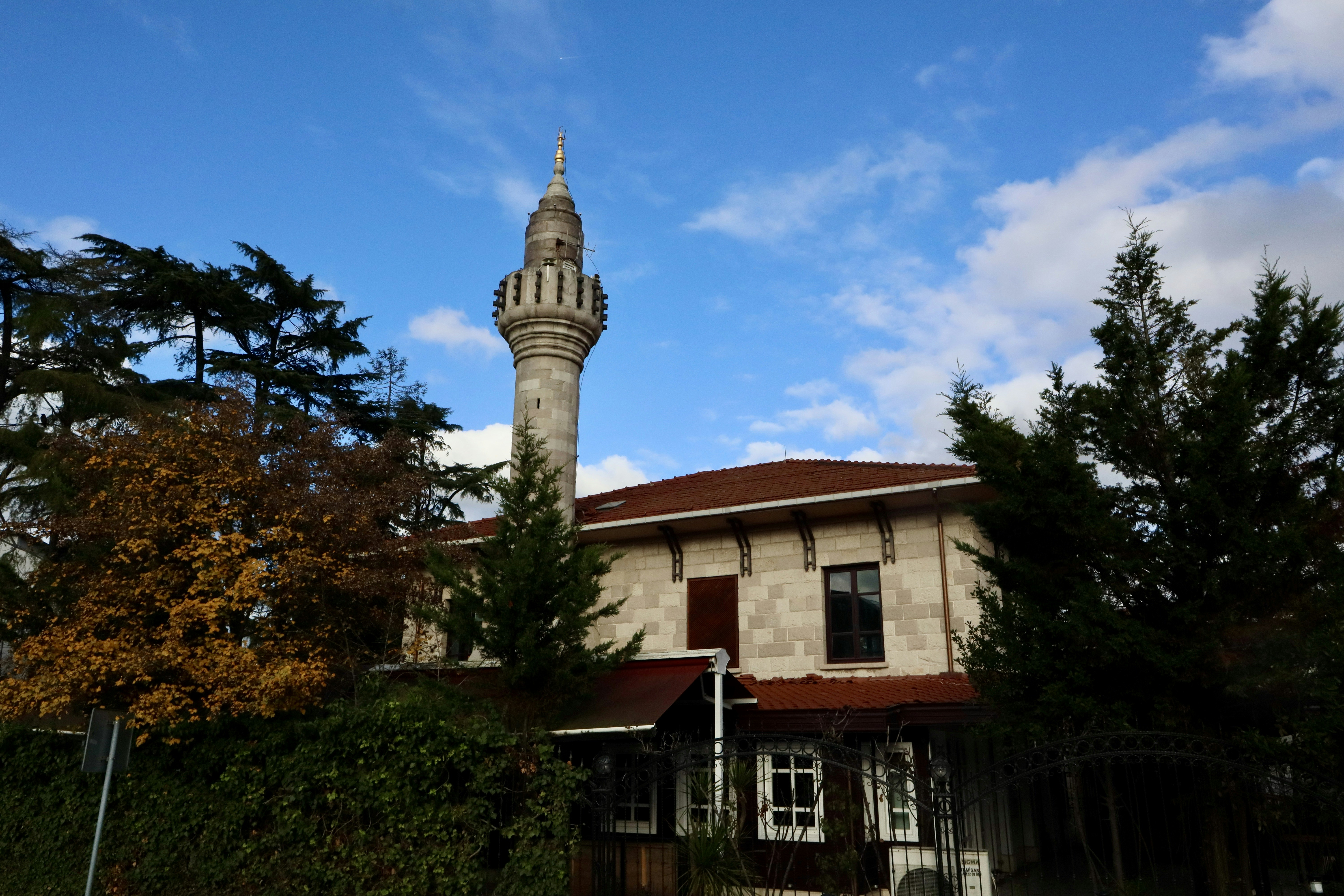 A mosque with a tall minaret under a cloudy sky.