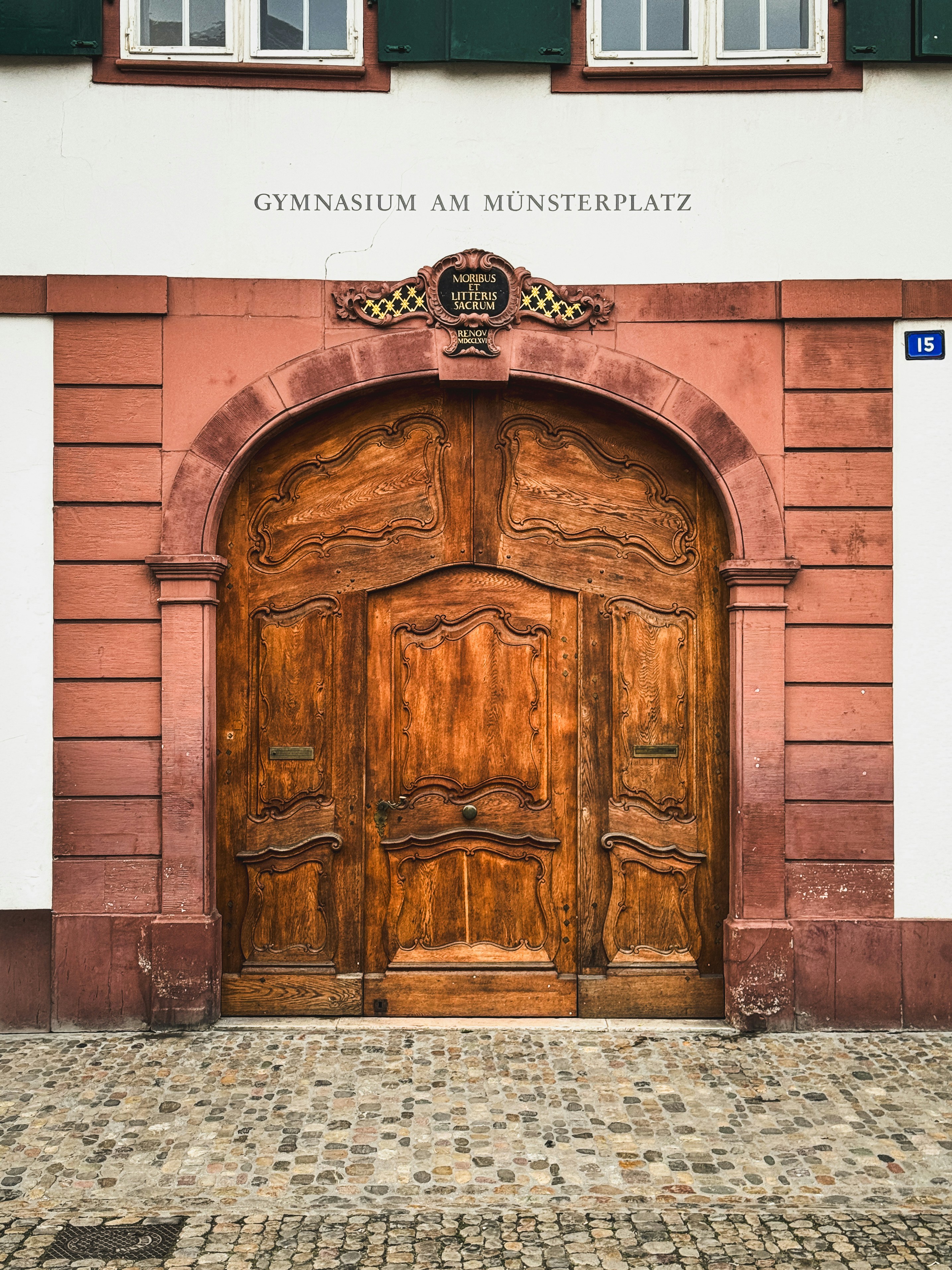 Gran puerta de madera ornamentada con arco de piedra.