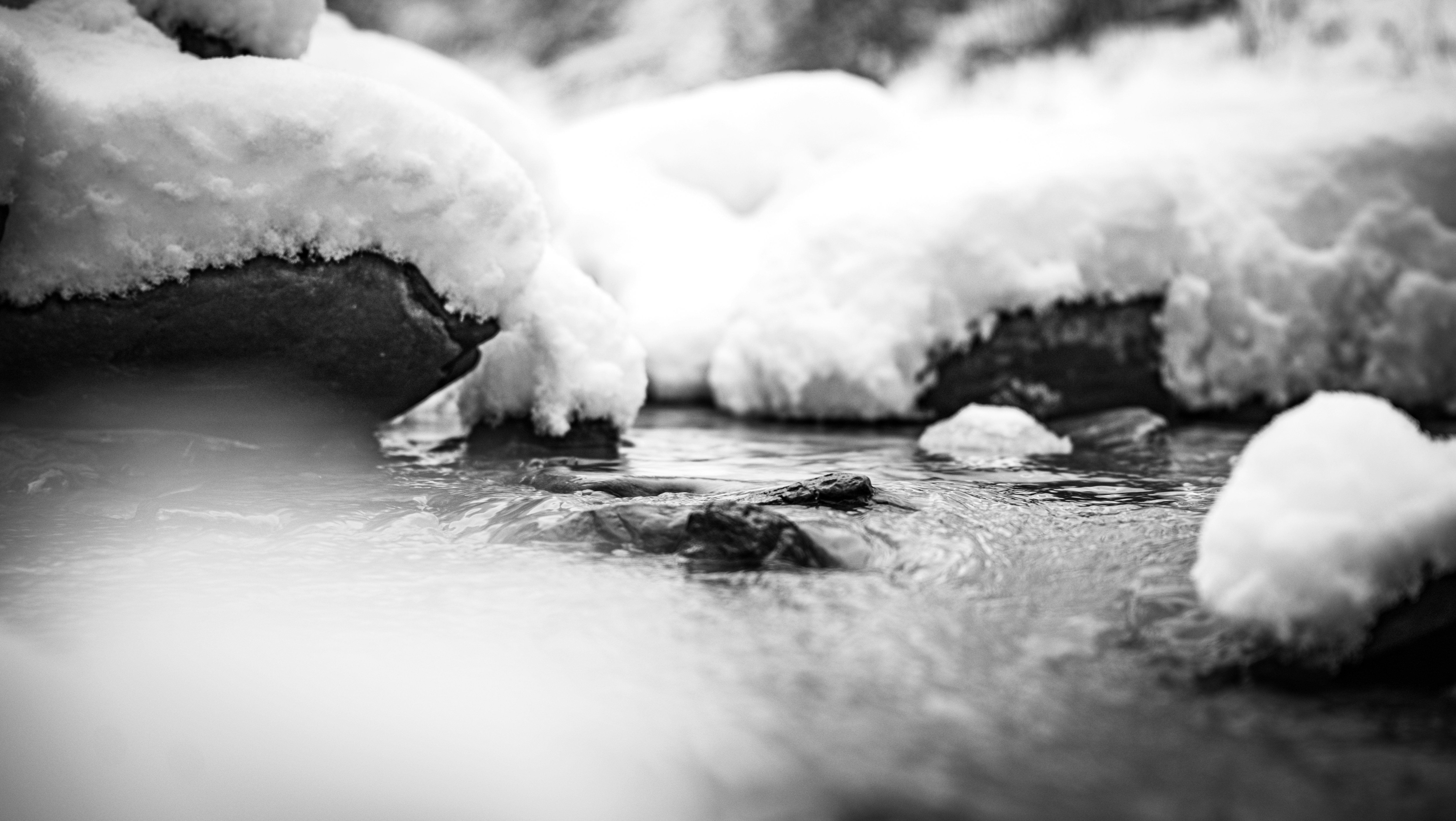Snowy stream with rocks and flowing water.