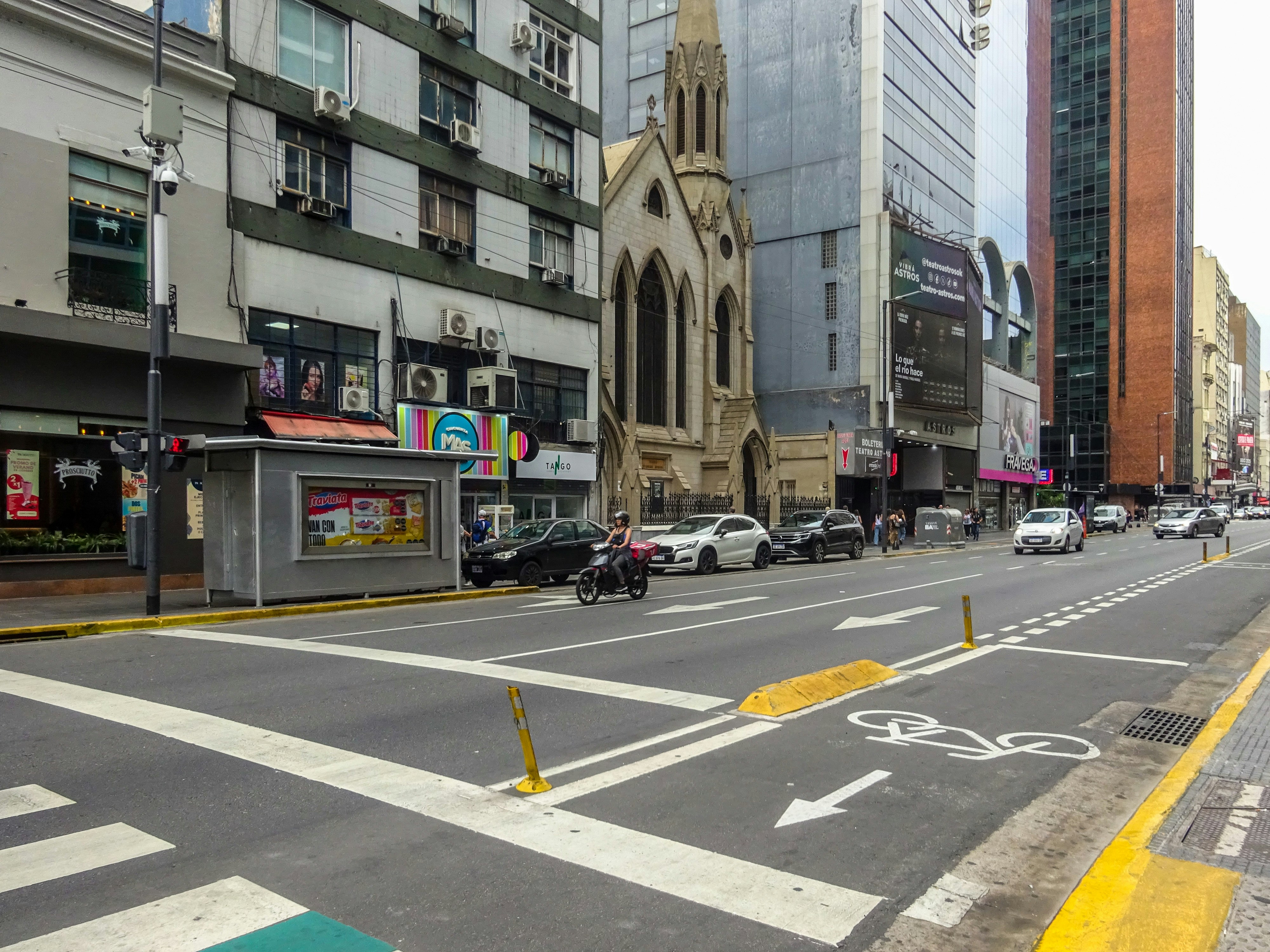 City street with buildings, cars, and a church.