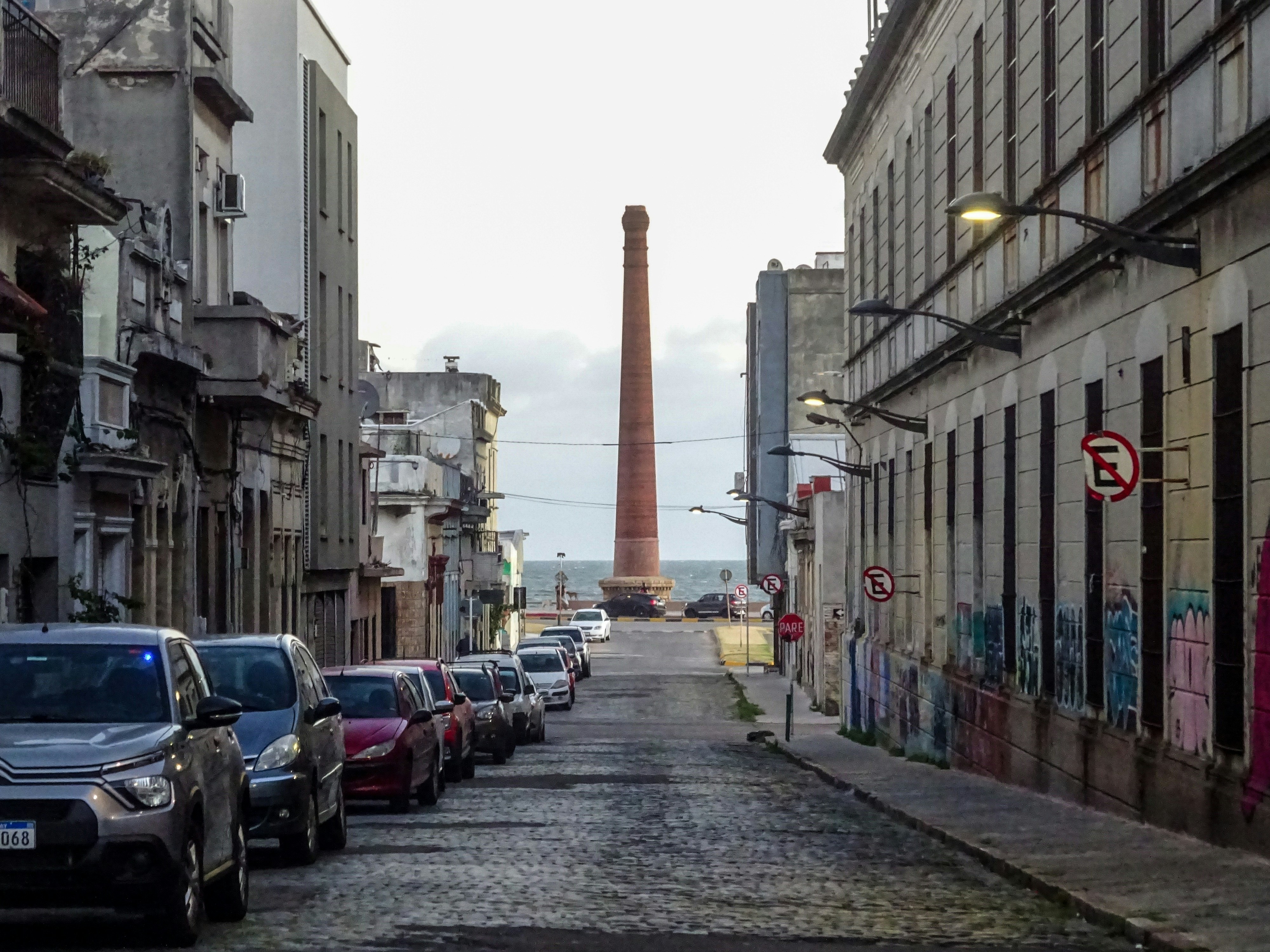 Tall brick chimney stands at the end of a street.
