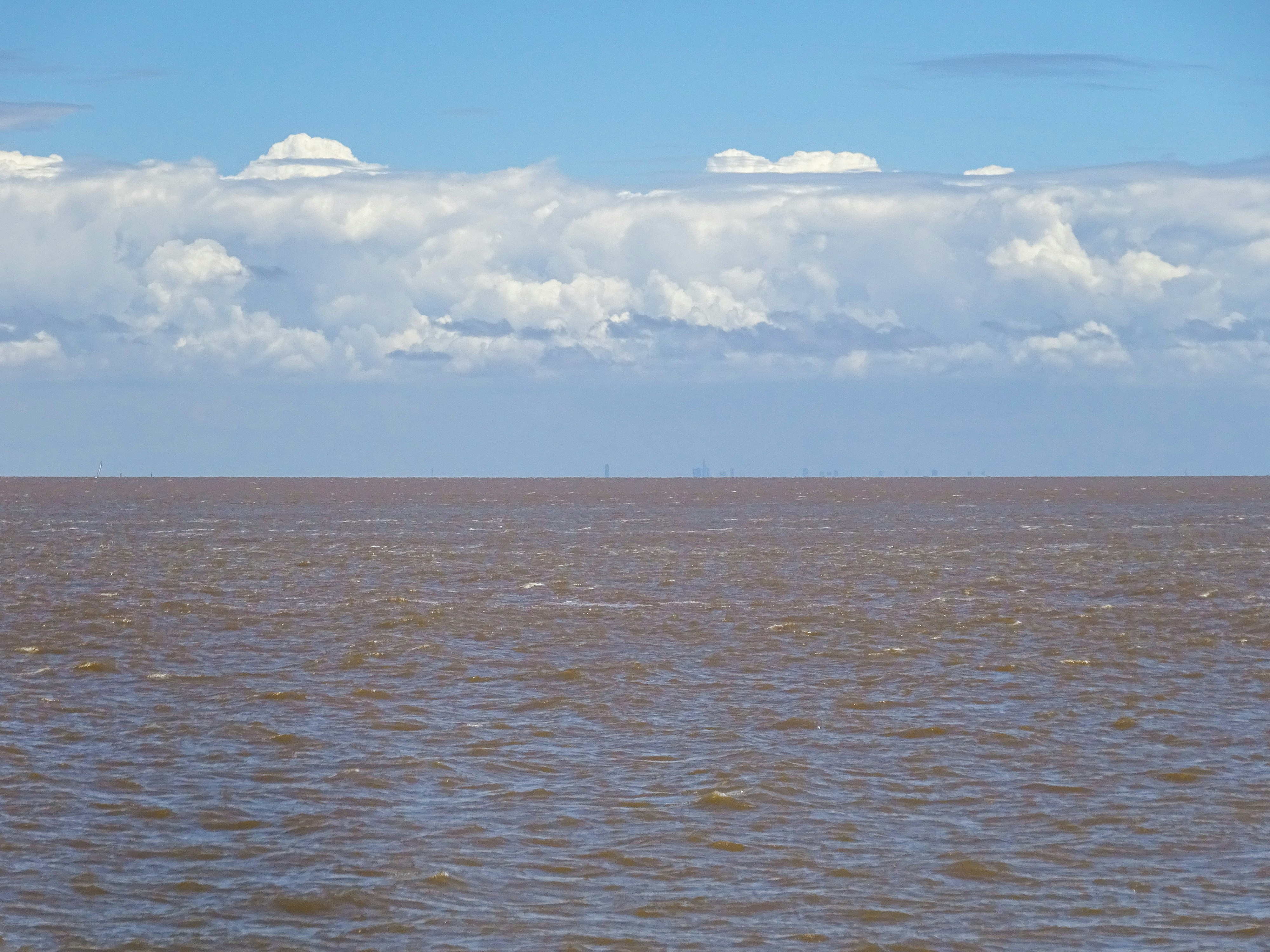 Brown ocean water under a cloudy blue sky - Colonia del Sacramento