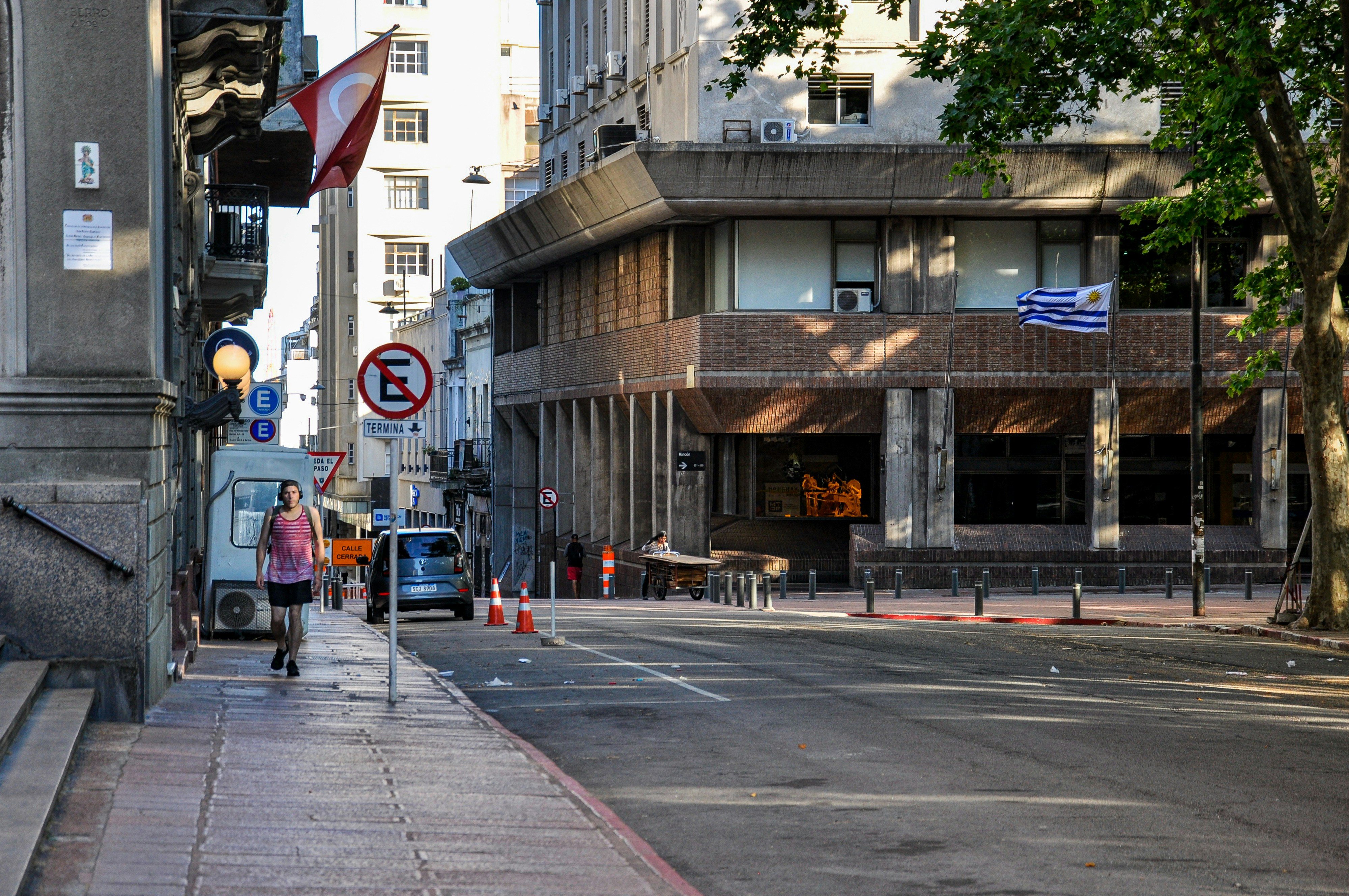 A woman walks down a city street next to buildings.