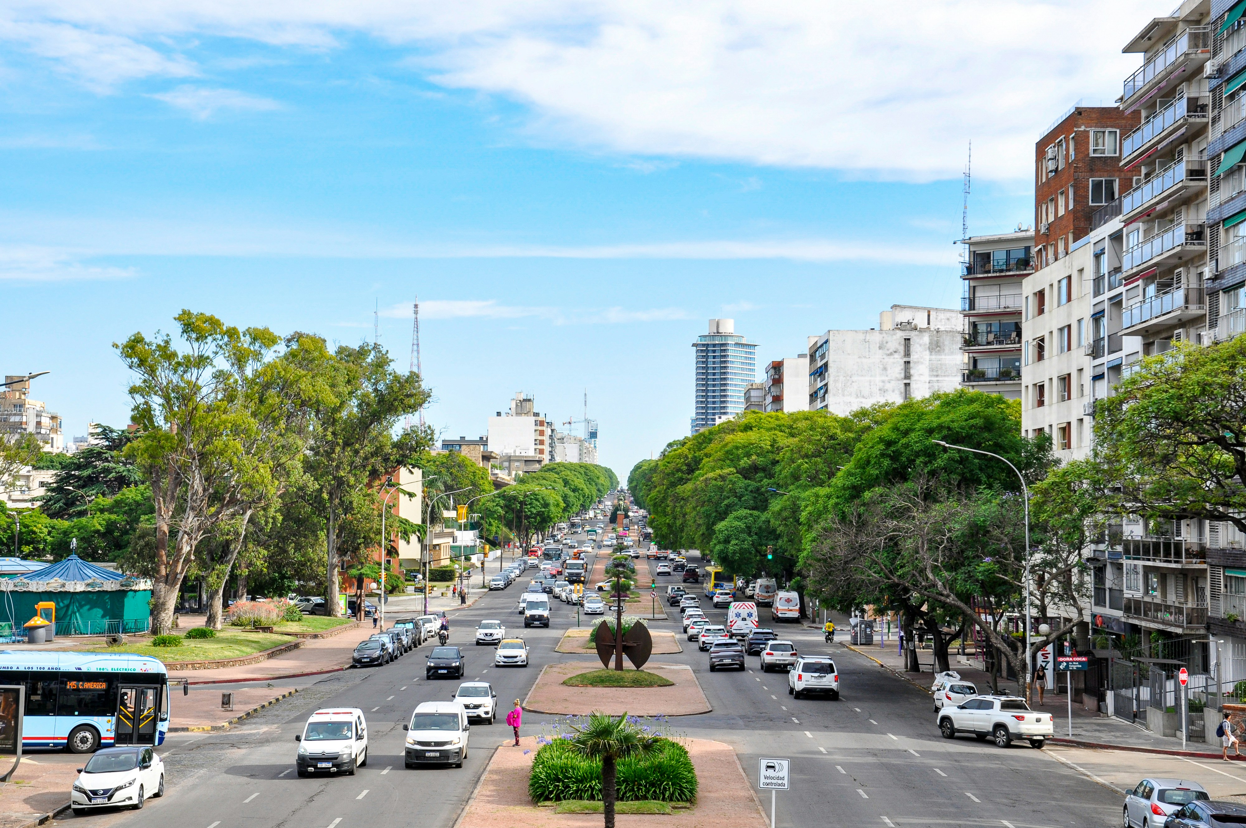 Busy city street with cars, trees, and buildings.