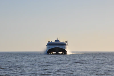 A modern catamaran ferry sails across the ocean.