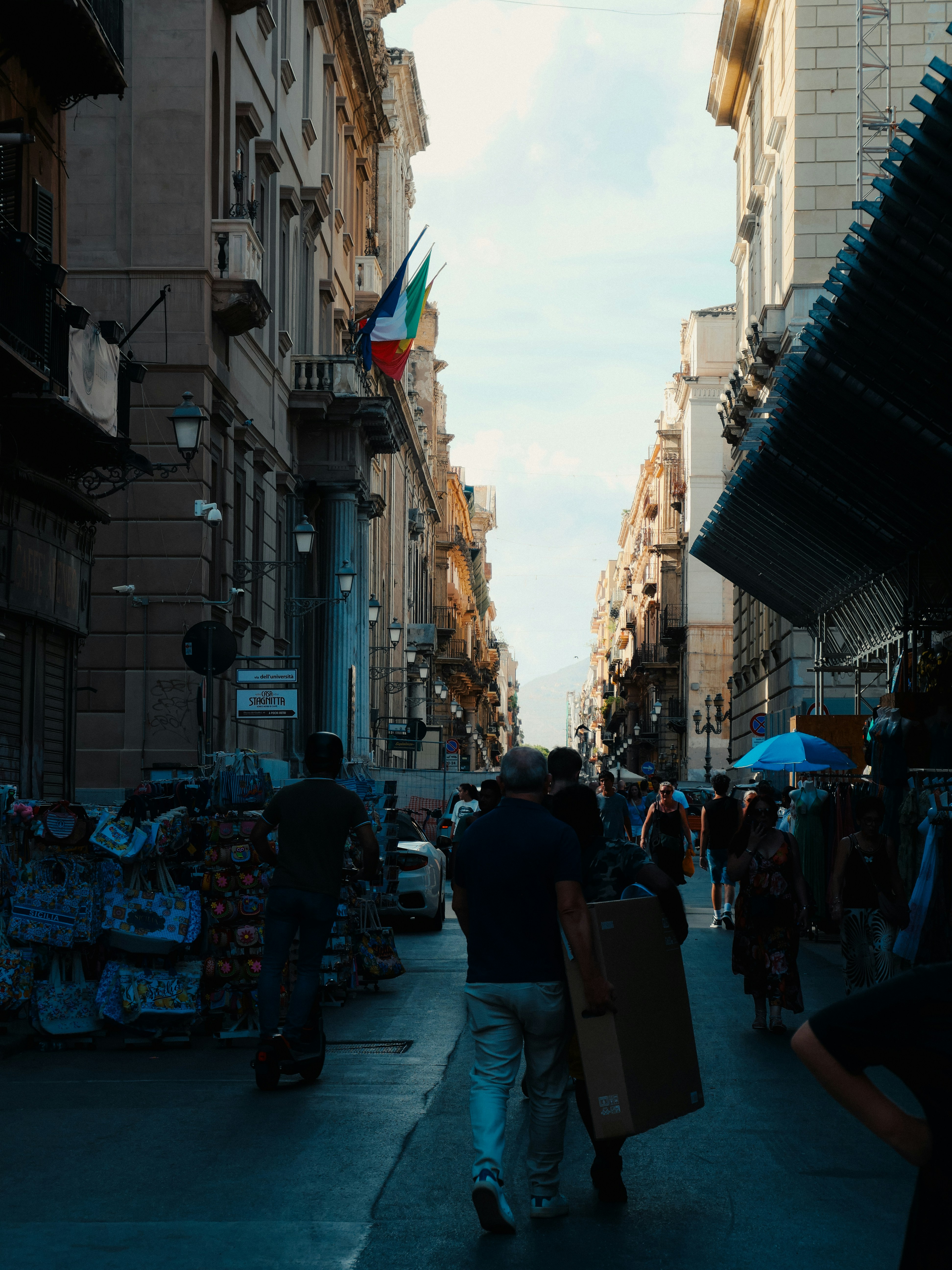 People walking down a narrow street lined with shops.