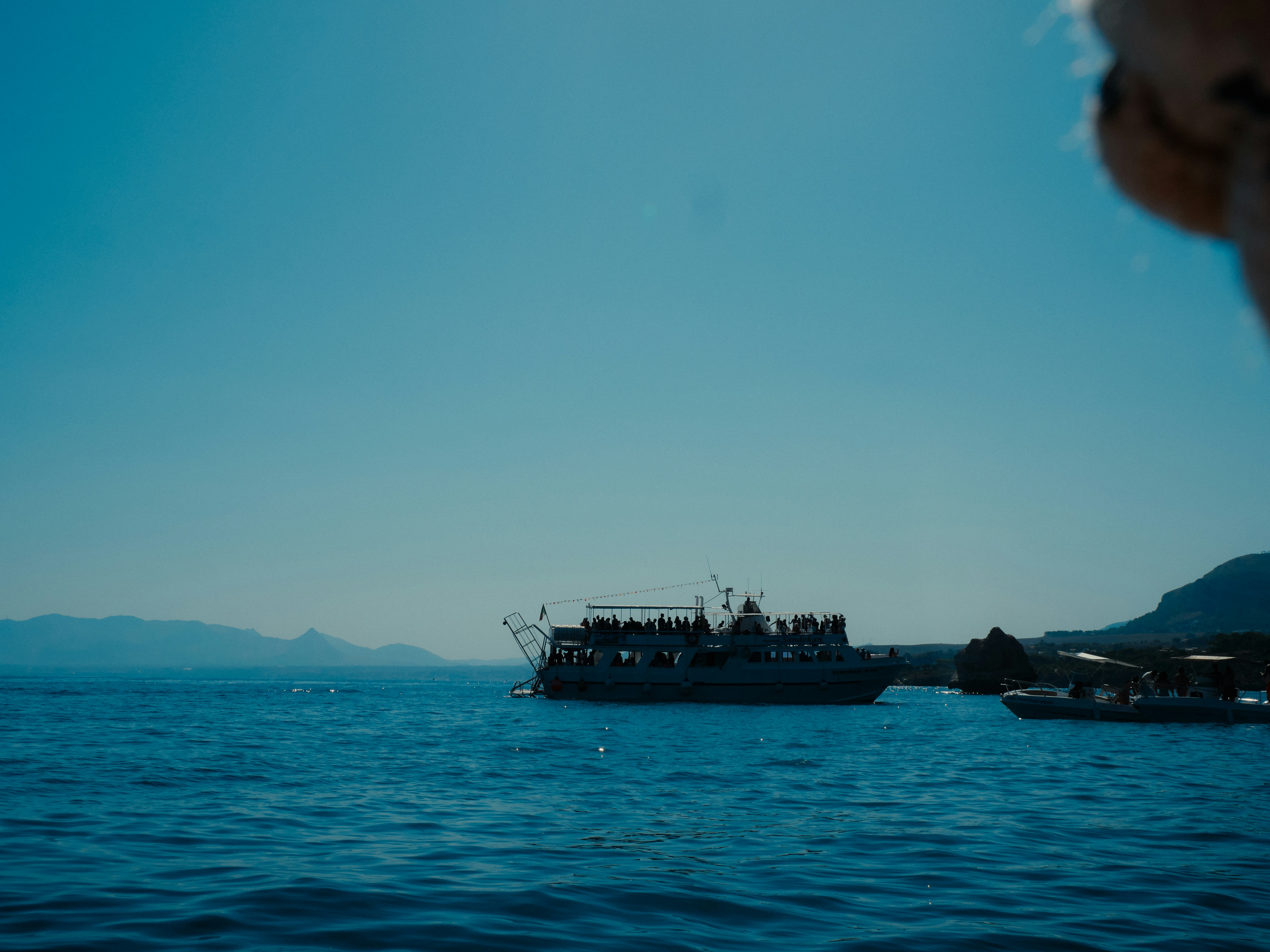A ferry boat sails across a clear blue ocean.