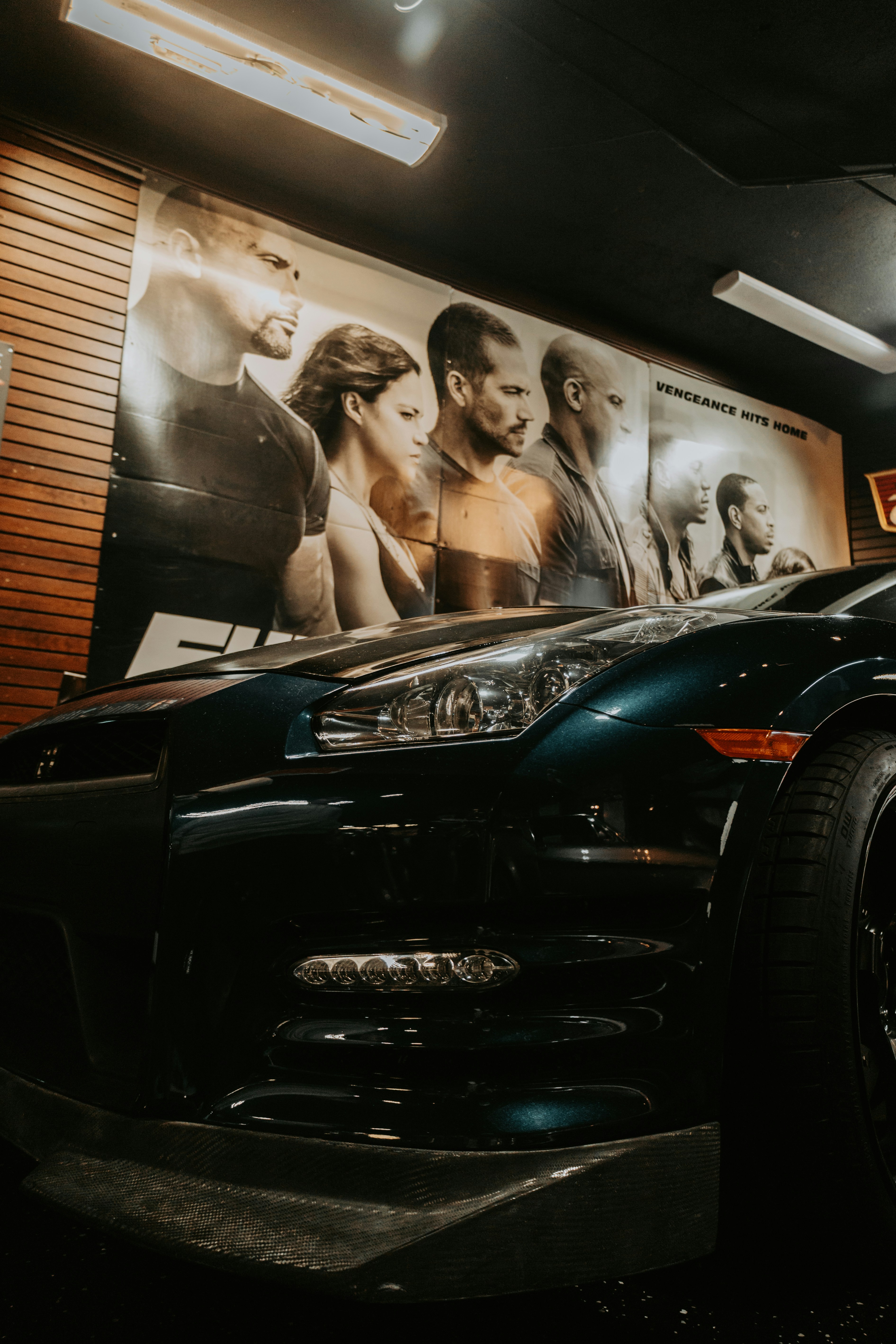 Dark blue sports car with movie posters in background