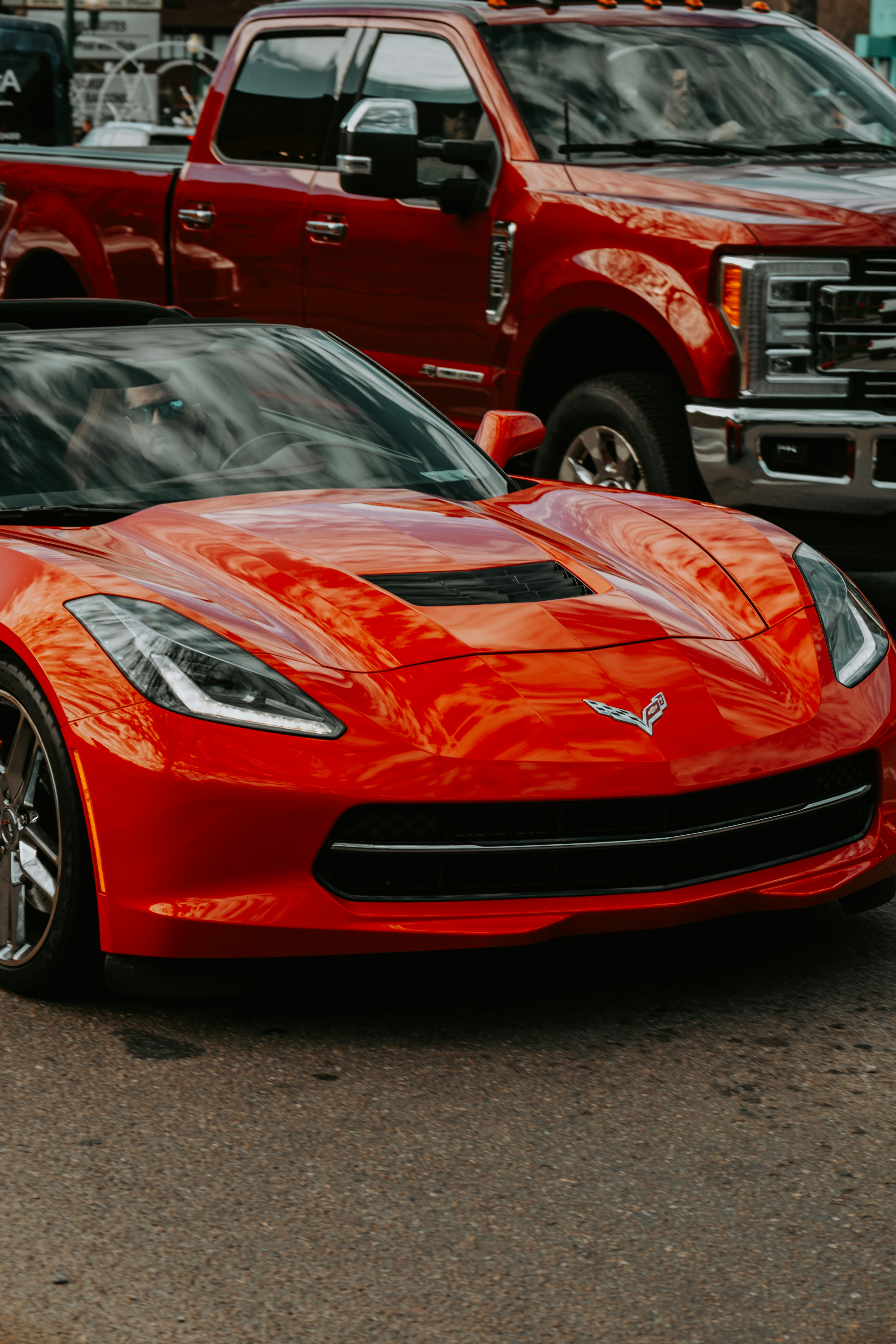 Roter Sportwagen vor einem roten Truck geparkt.