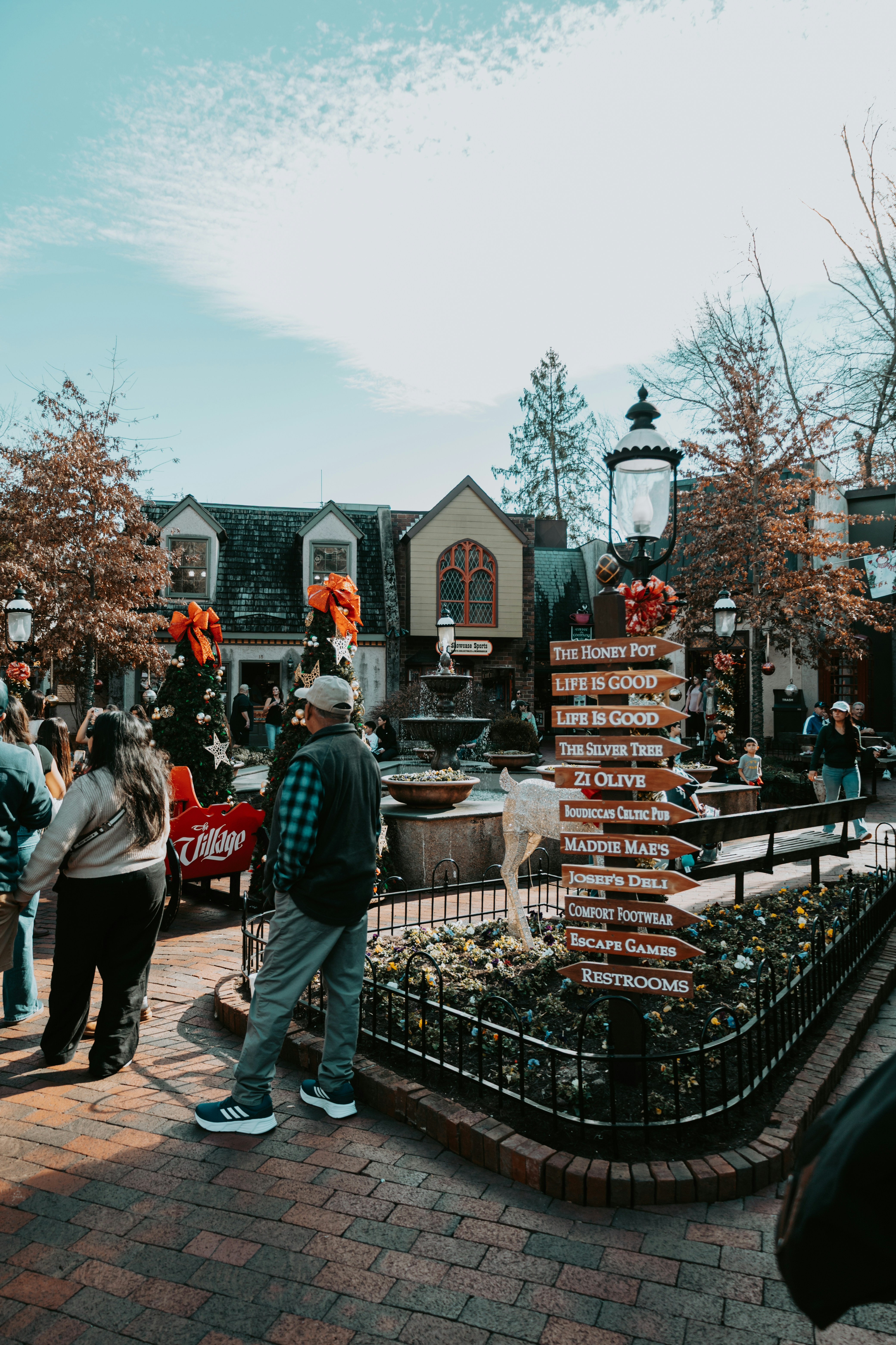 Menschen, die auf einem Marktplatz mit Wegweiserschildern spazieren.