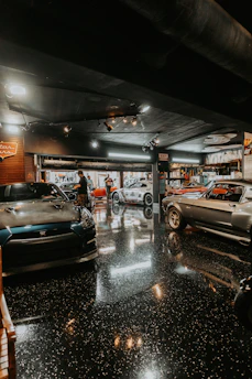 Several classic cars parked inside a garage High-gloss, mirror-like epoxy finish reflect bright over
