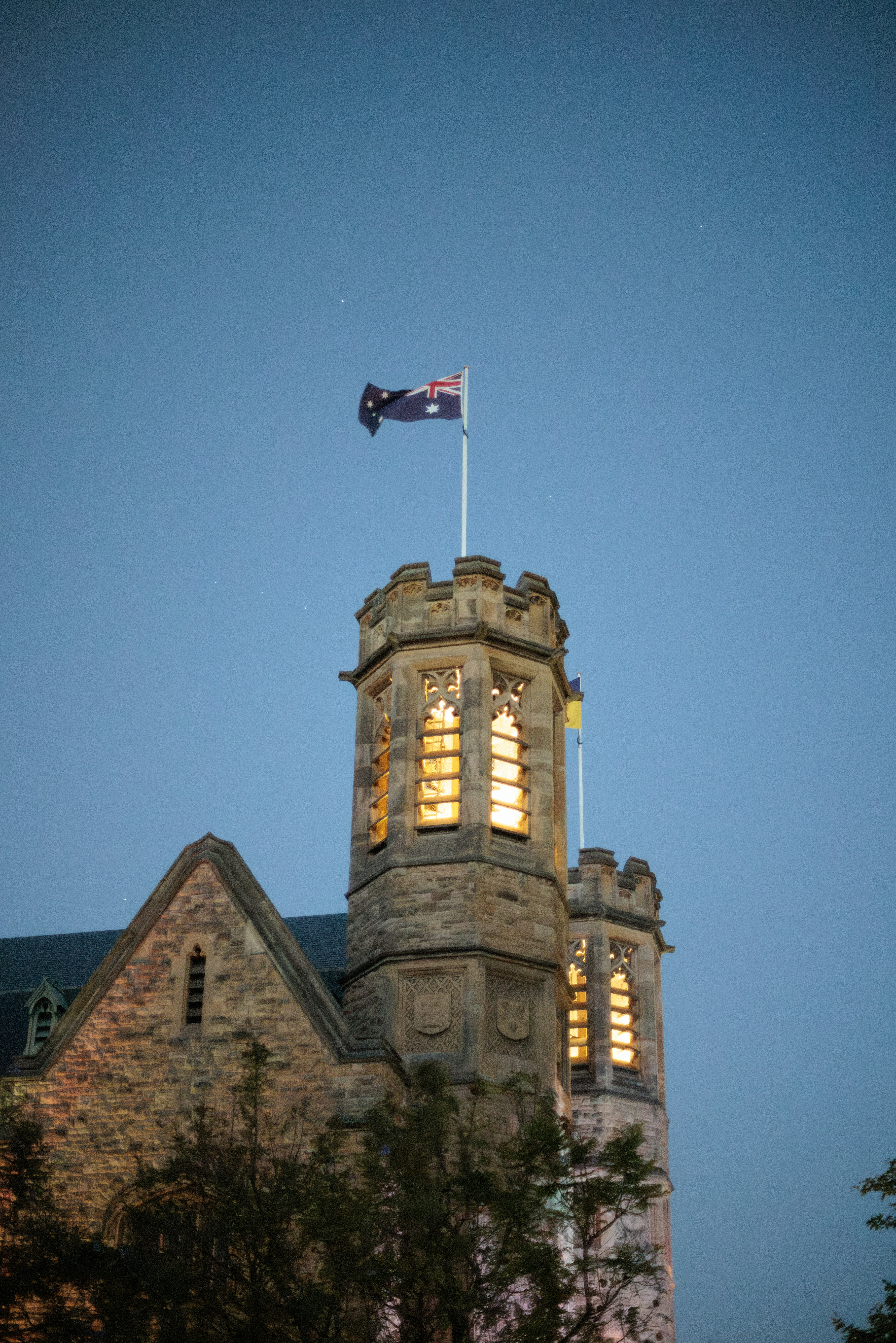 Torre de pedra do castelo com bandeira contra o céu do crepúsculo