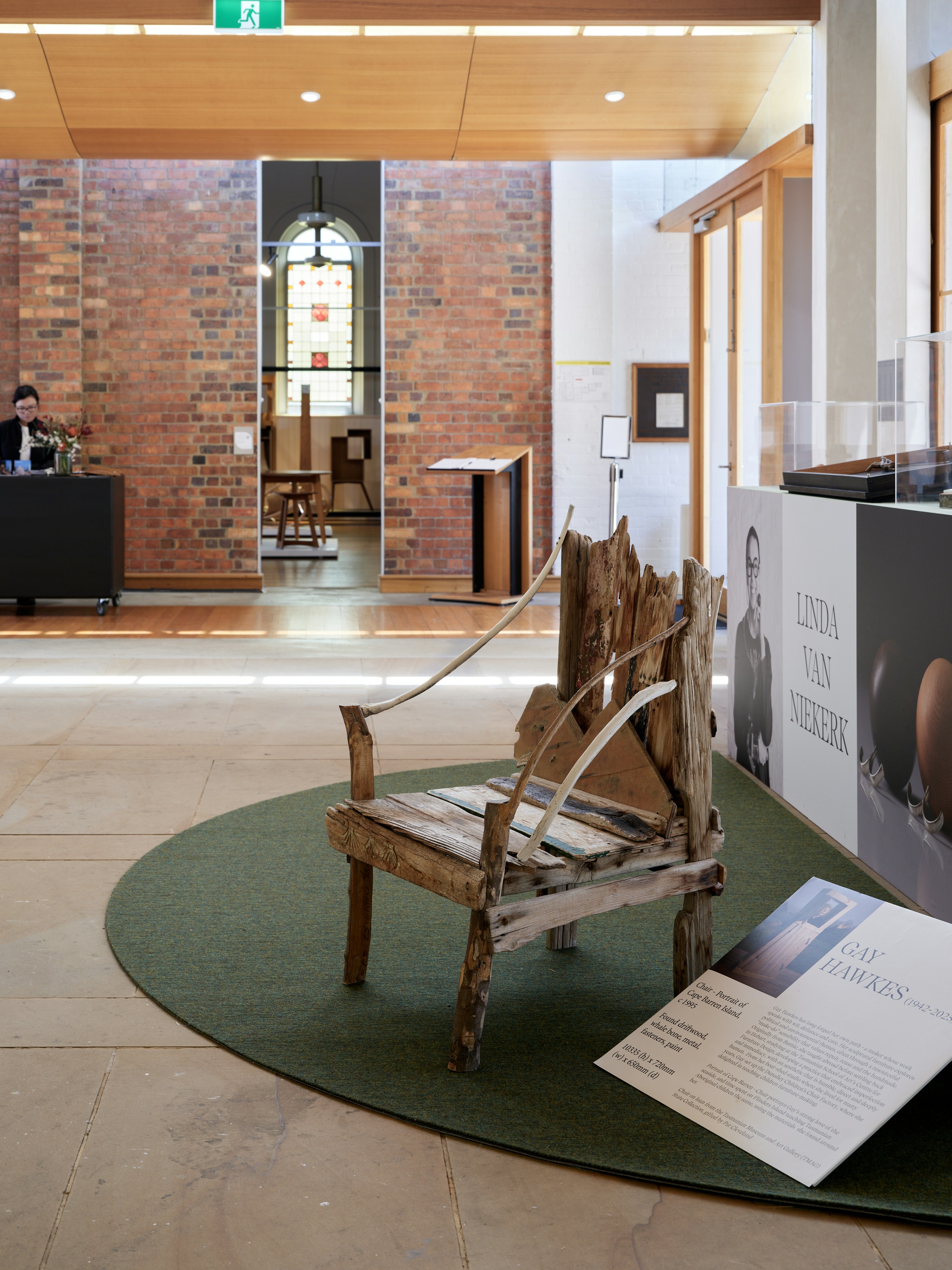 Rustic wooden chair displayed in a museum setting.