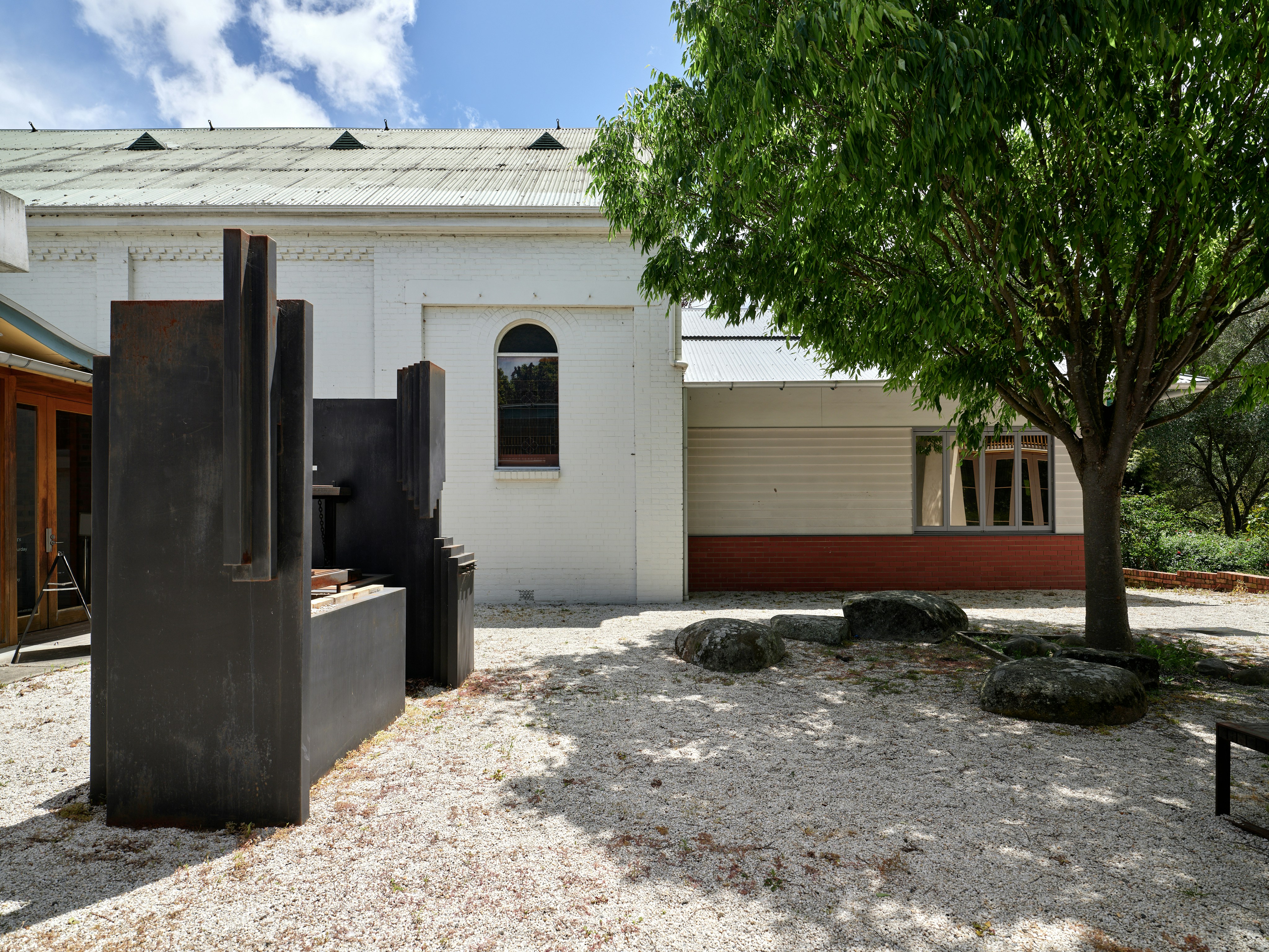 Modern sculpture in a courtyard with a tree
