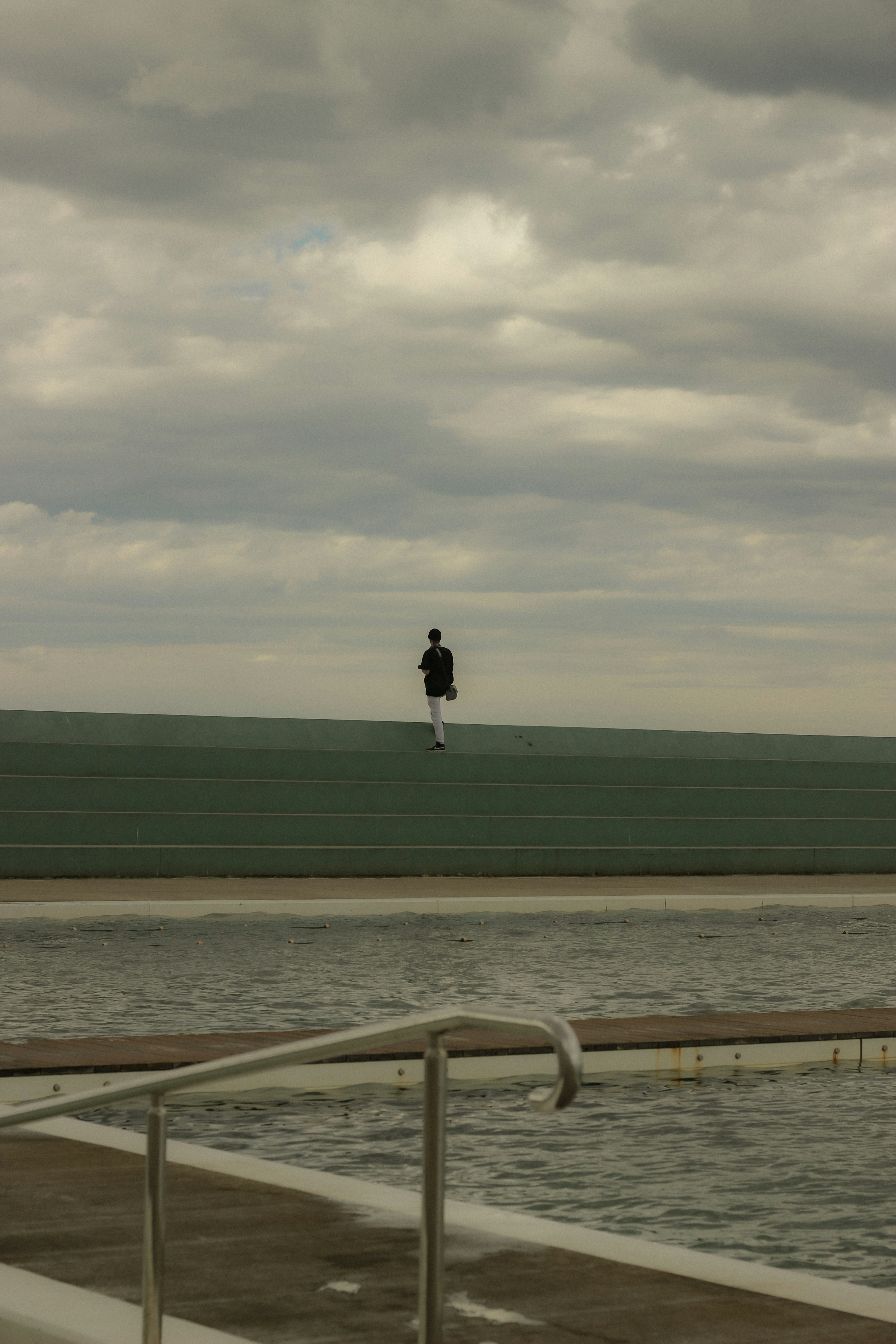 Persona caminando sobre una pared verde cerca del agua