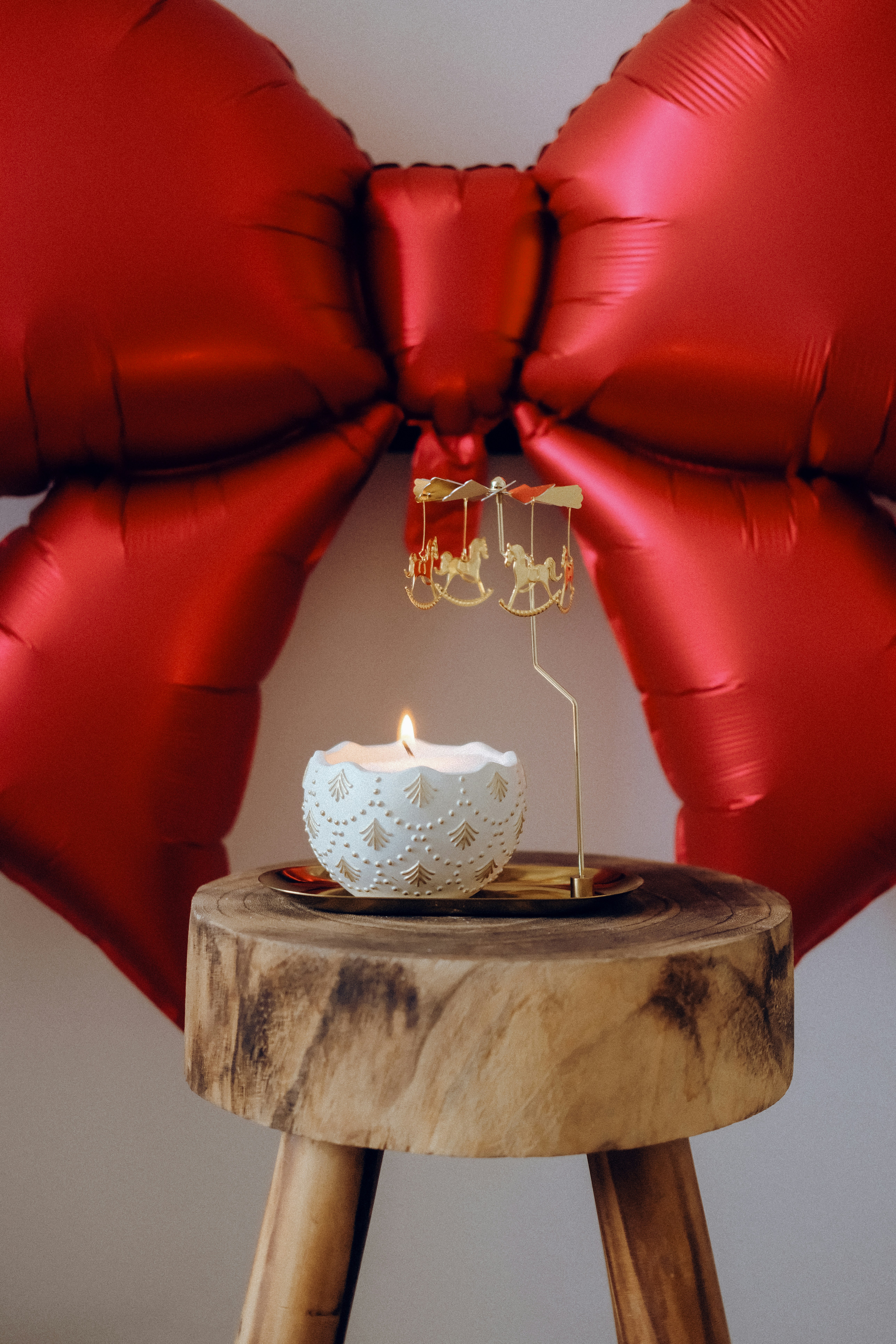 Lit candle with rocking horse decoration and red bow