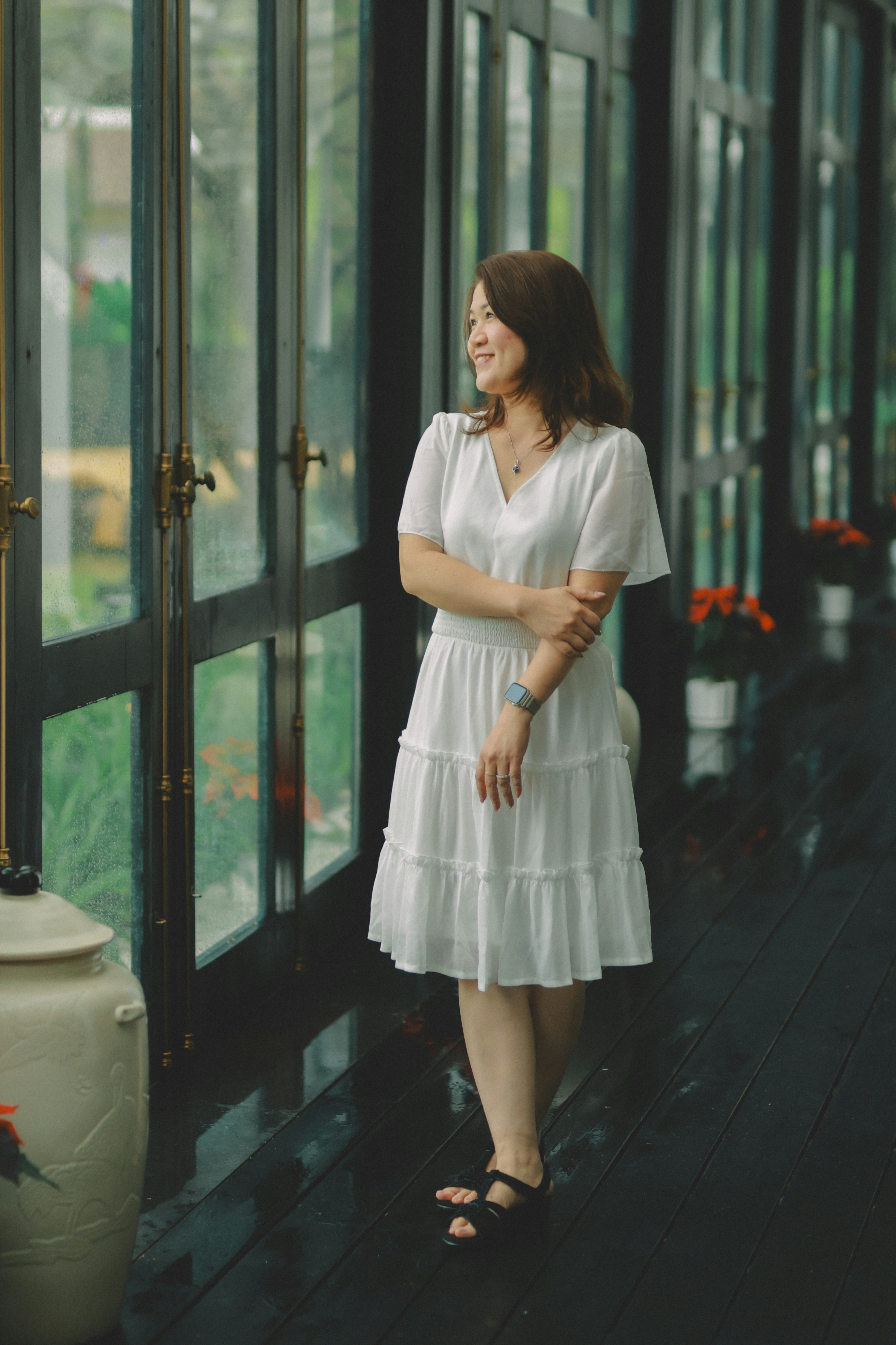 A woman in a white dress looking out window