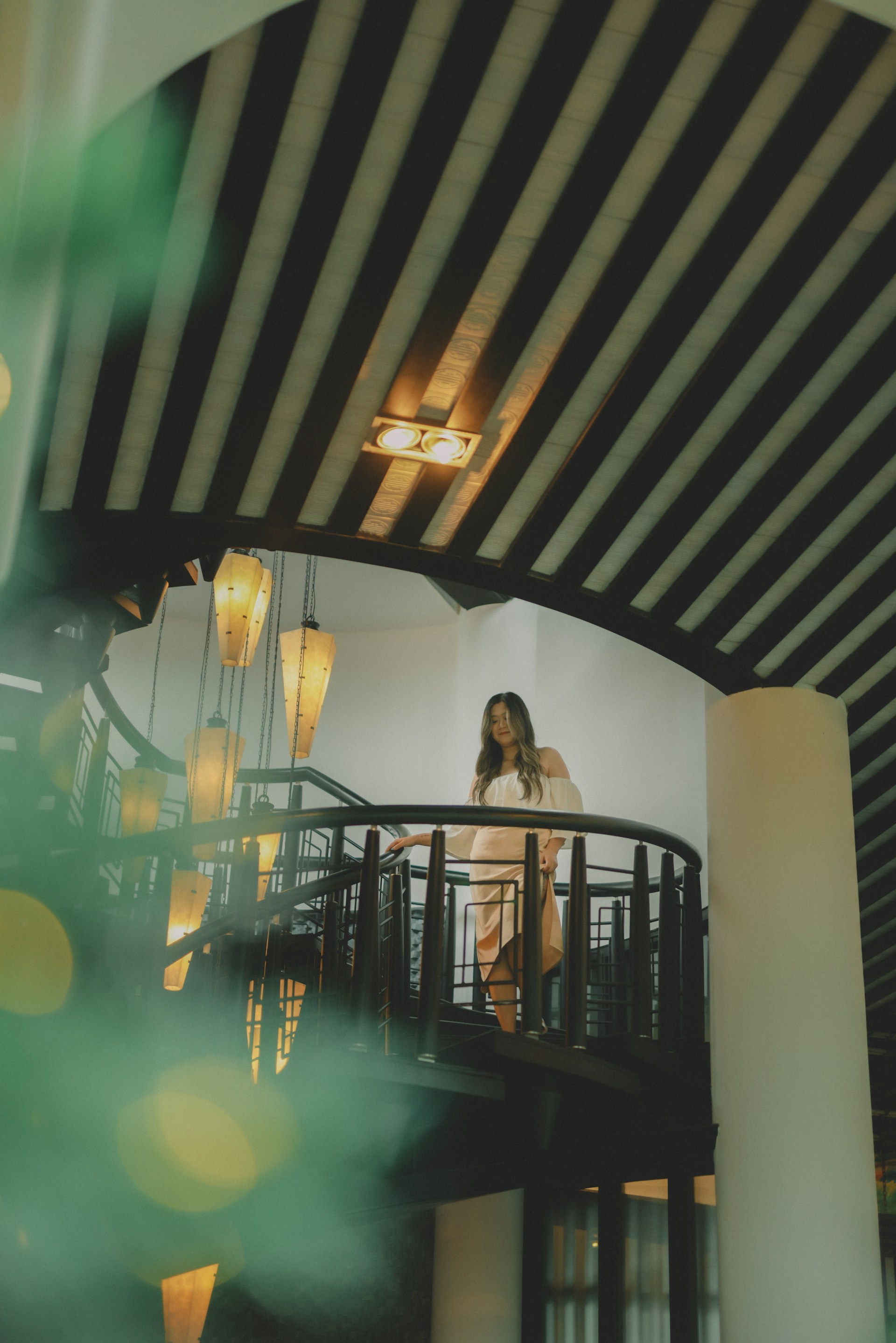 Woman standing on a spiral staircase indoors.