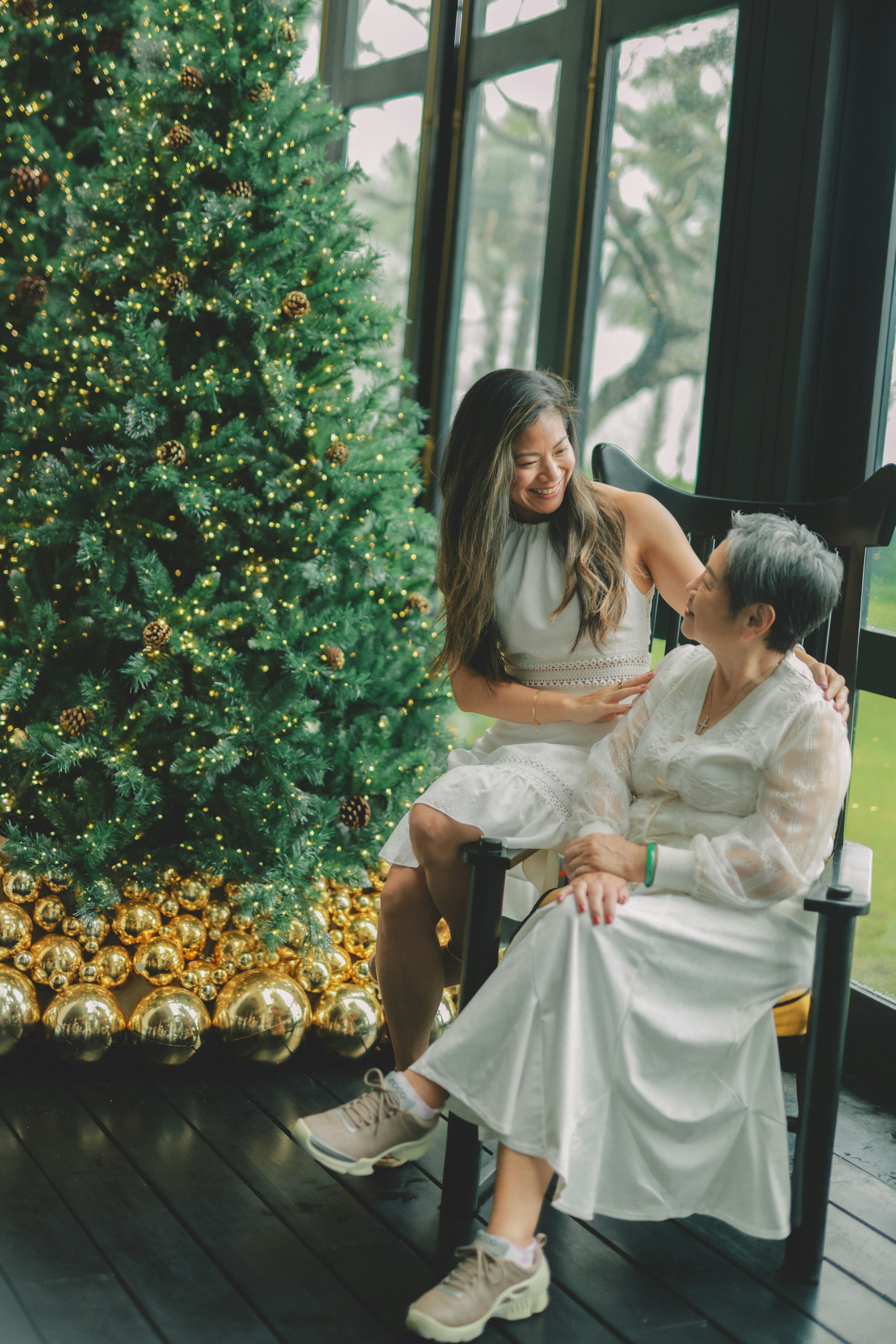 Two women smiling by a christmas tree