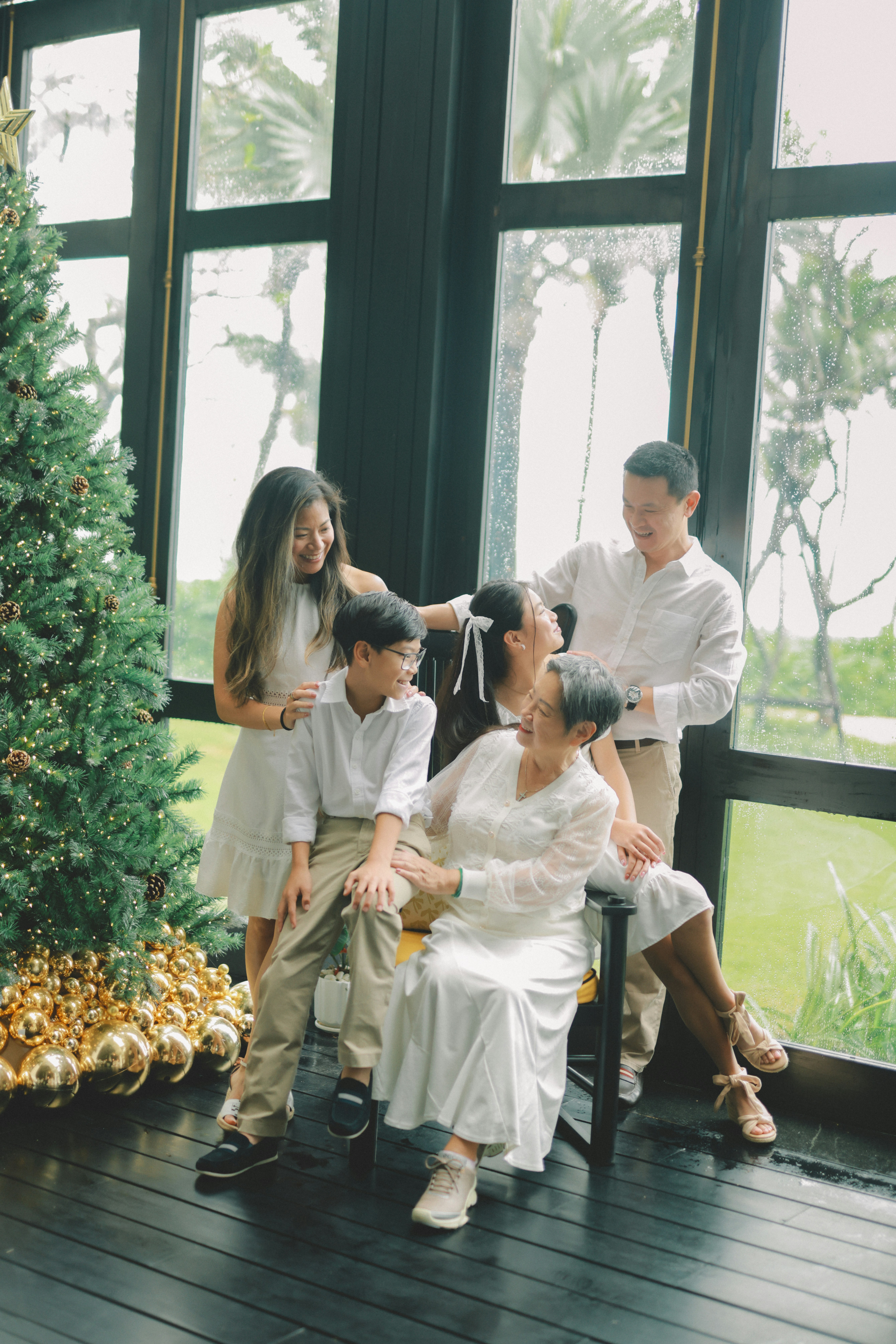 A family poses by a christmas tree indoors.