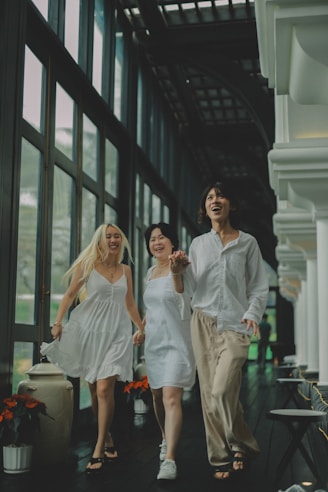 Three women in white dresses running and laughing together.