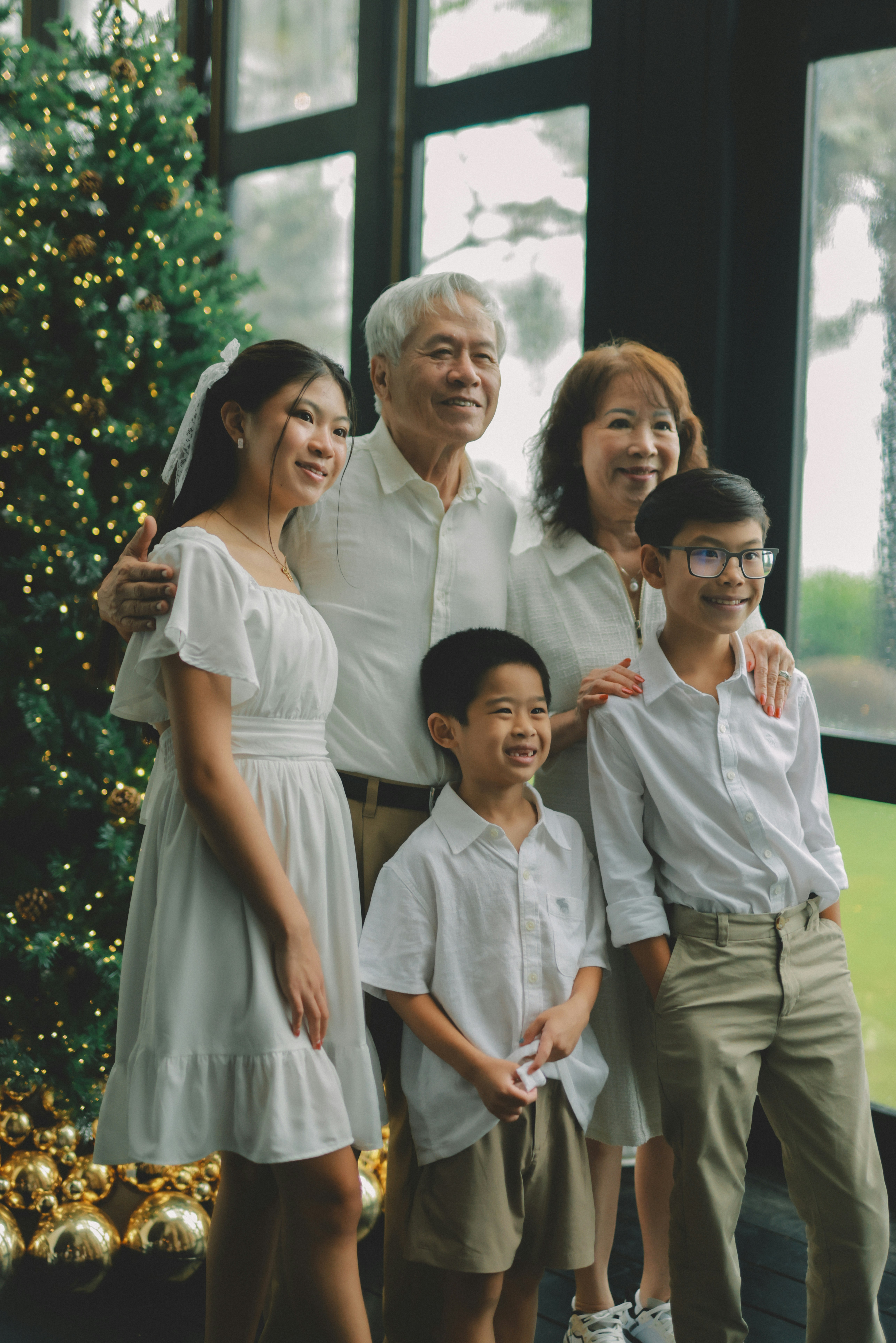 A multi-generational family poses by a christmas tree.