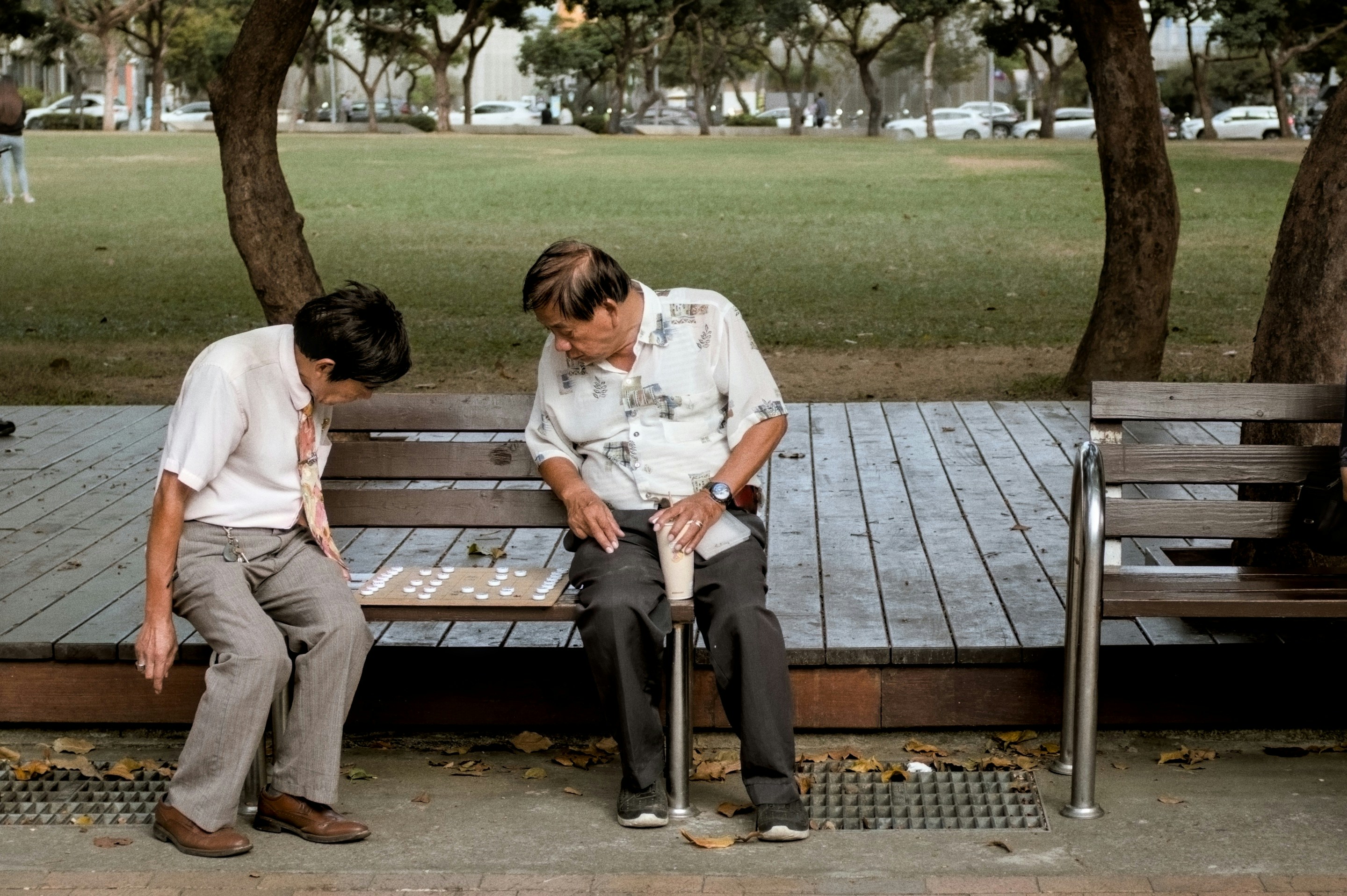 Two men playing checkers on a park bench.