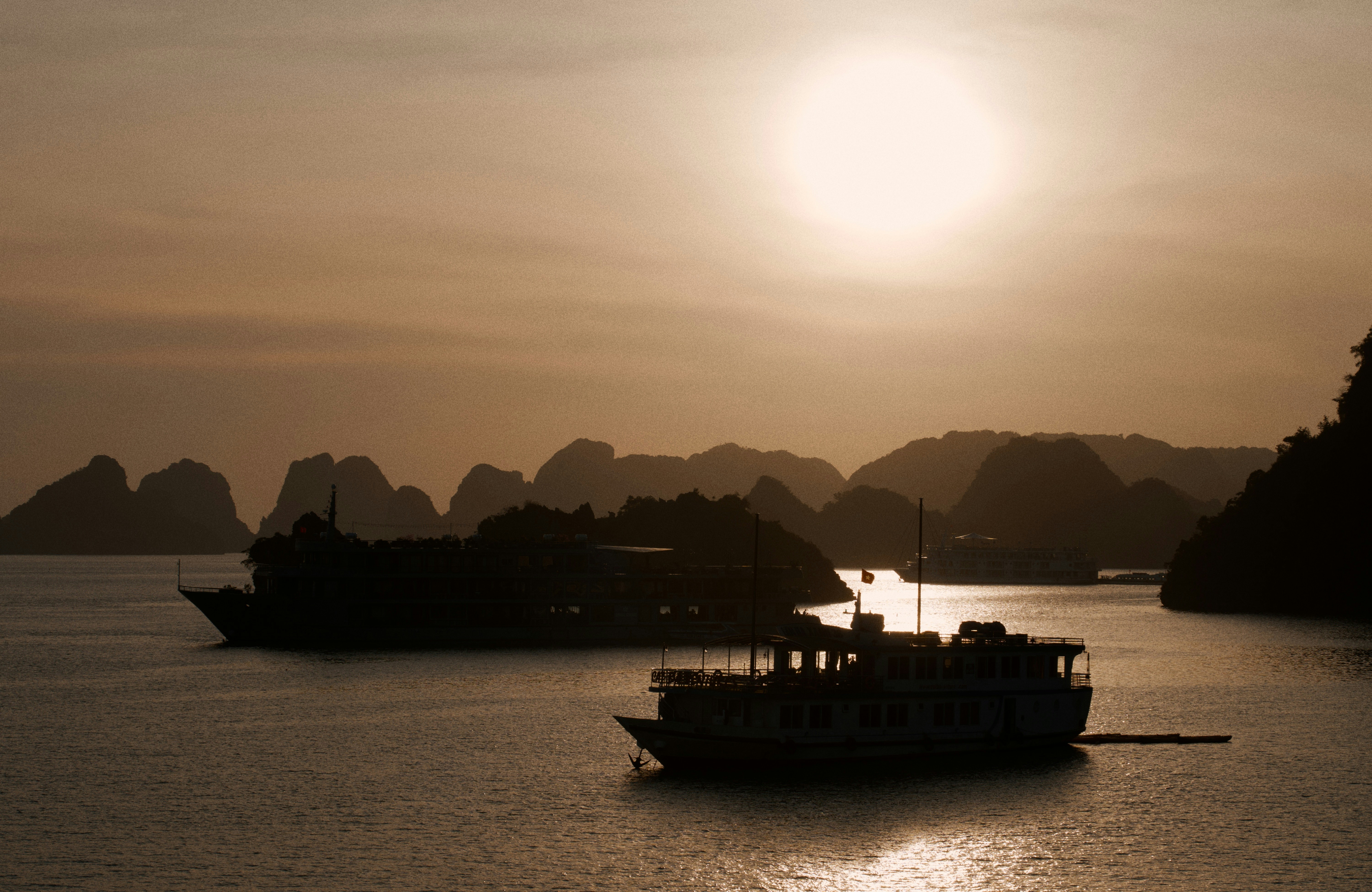 Two boats sail on the water at sunset.