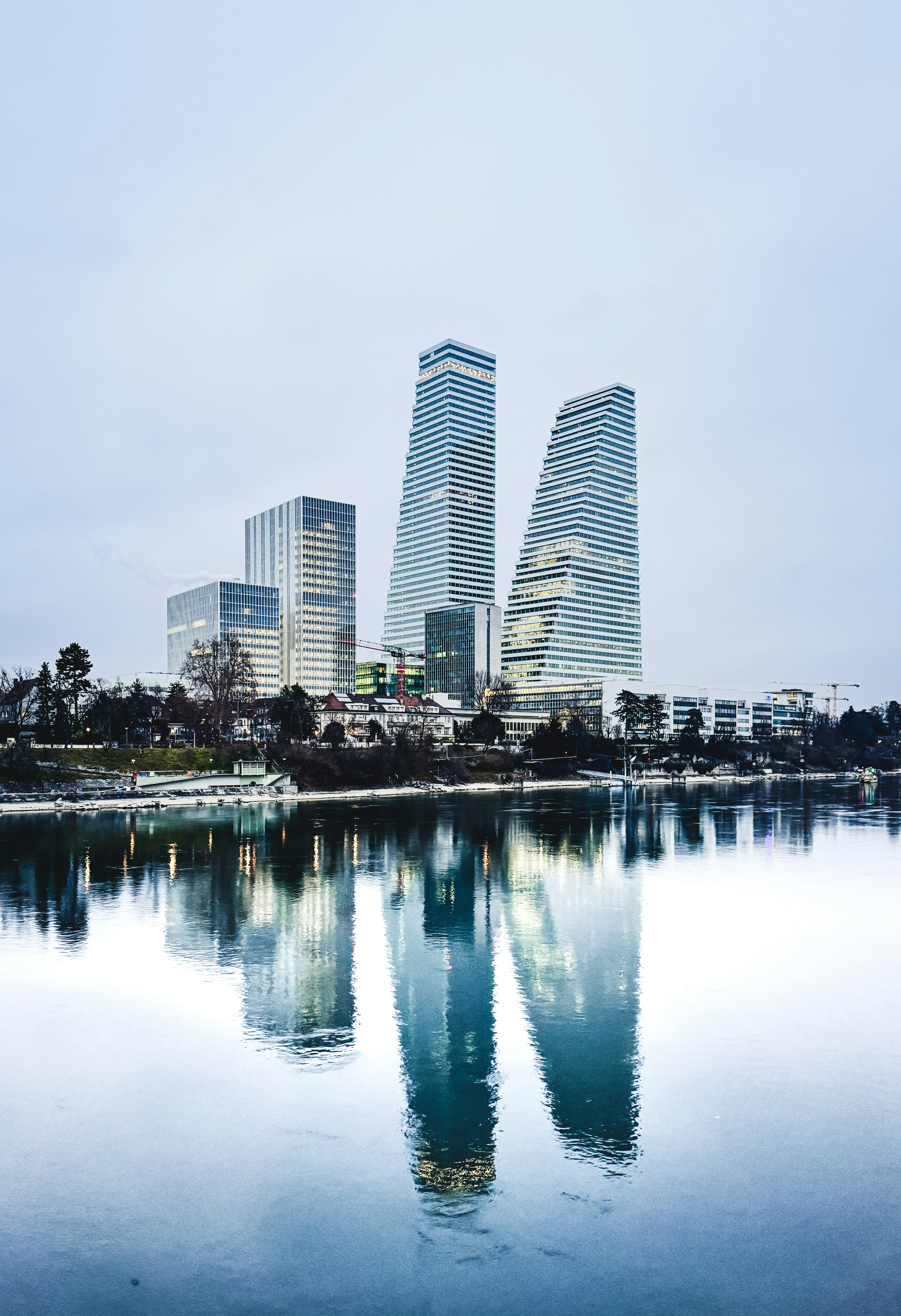 Rascacielos modernos reflejados en aguas tranquilas en un día nublado