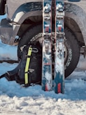 Skis and backpack leaning against a car tire