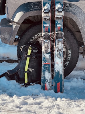Skis and backpack leaning against a car tire