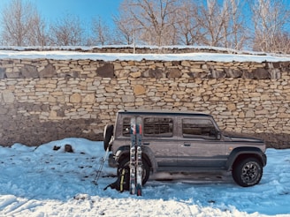 Silver suv parked in snow with skis nearby