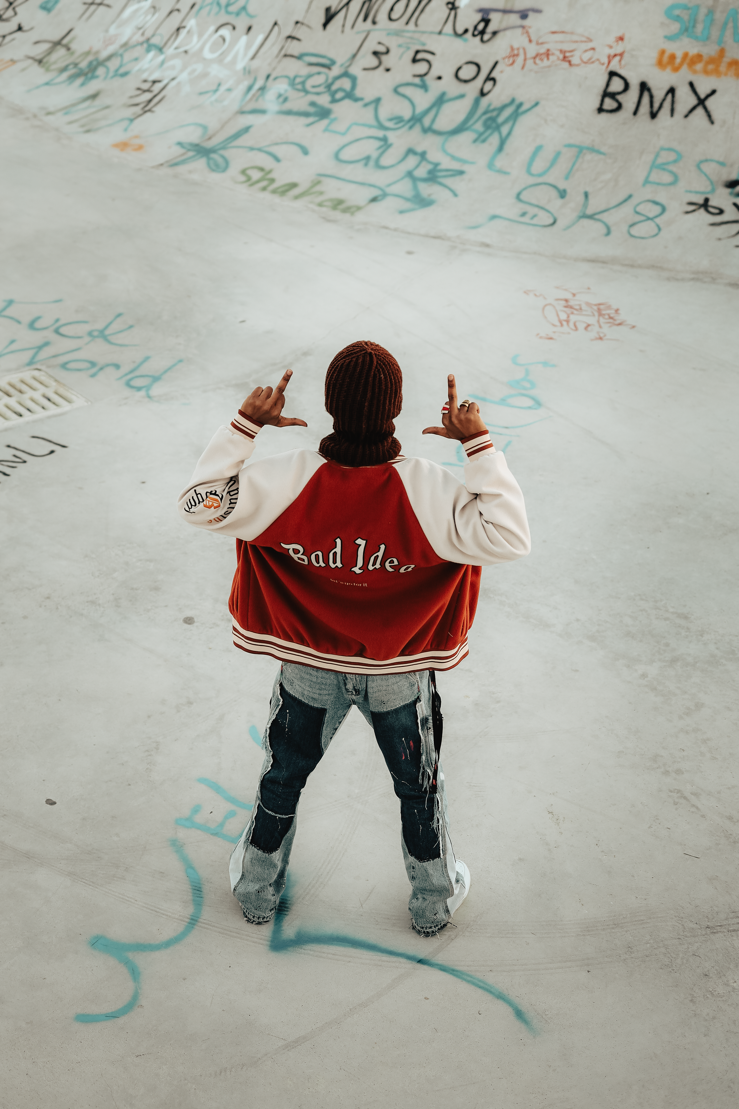 Person in varsity jacket at graffiti-covered skatepark