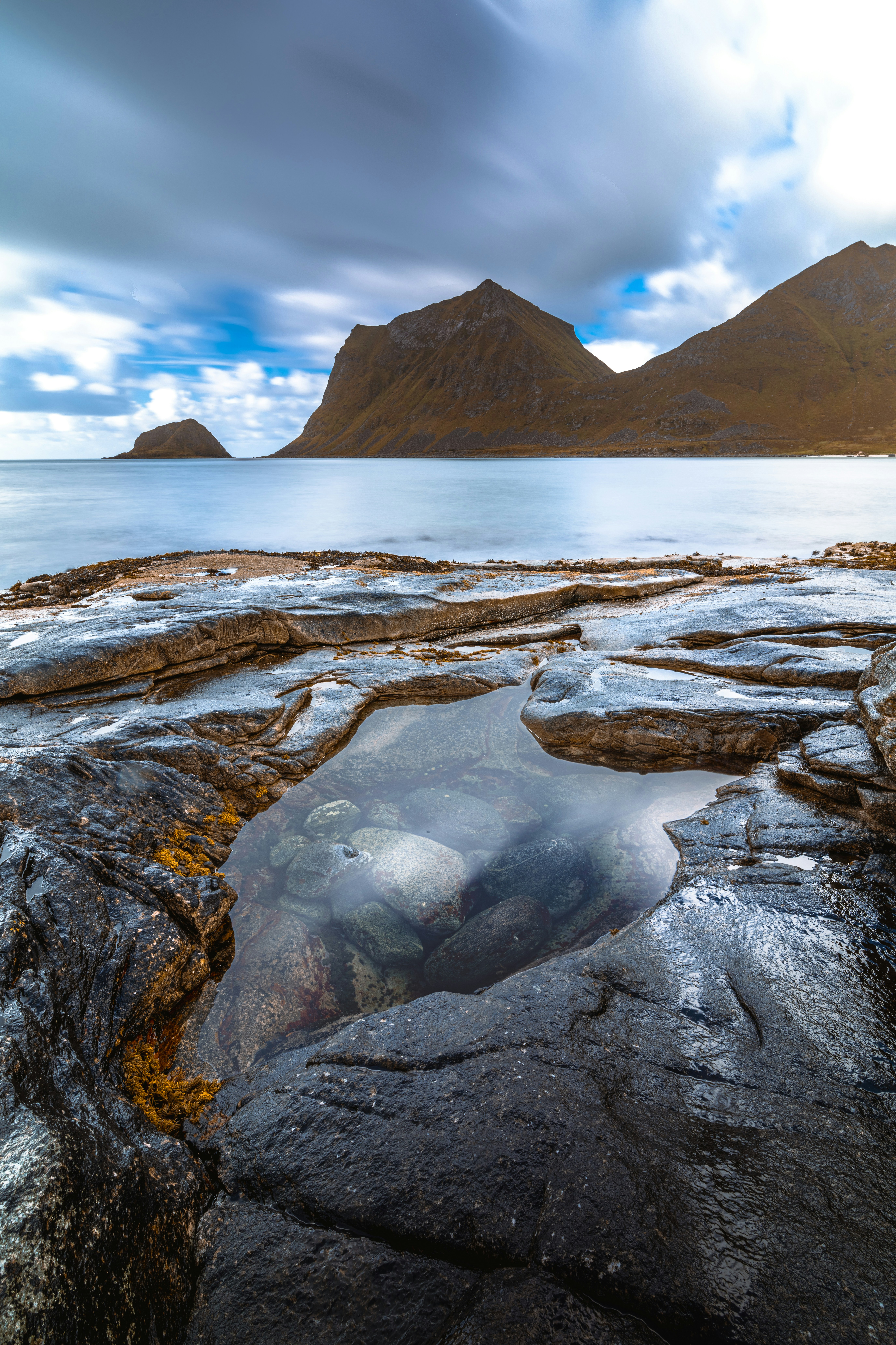 Costa rocosa con poza de marea y montañas lejanas