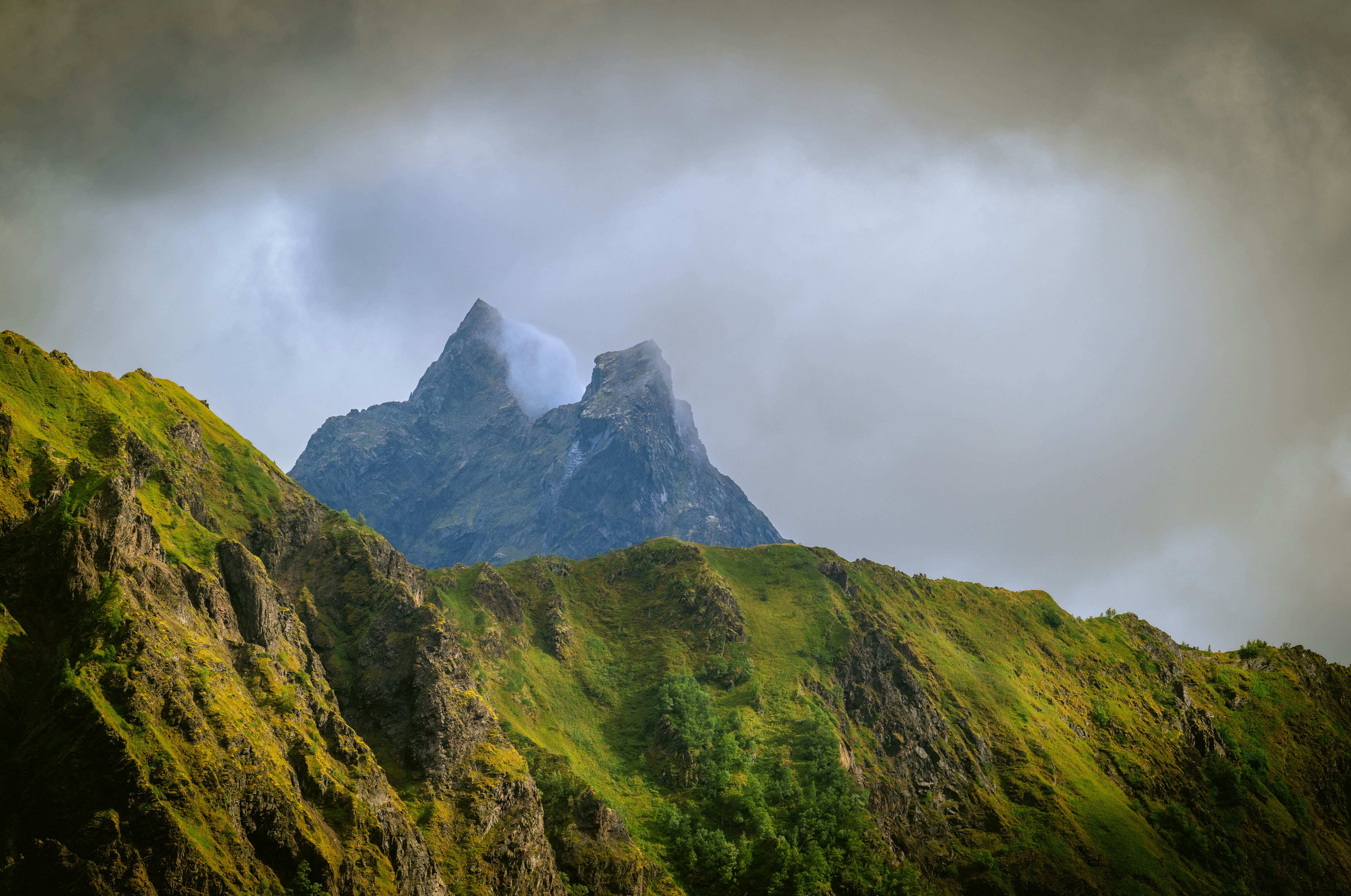 Cumbres montañosas escarpadas envueltas en nubes dramáticas