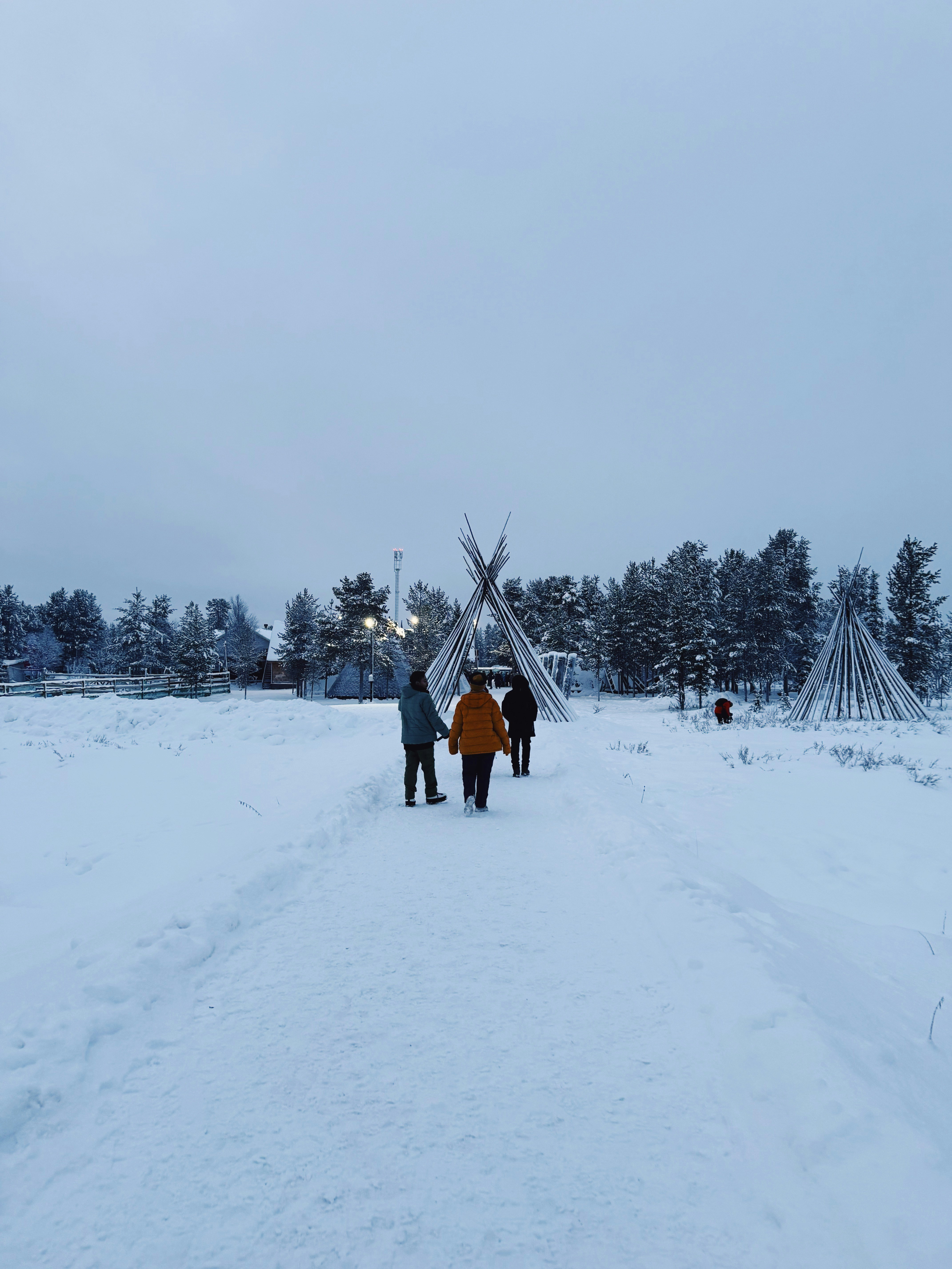 La gente camina hacia tipis en un paisaje nevado.
