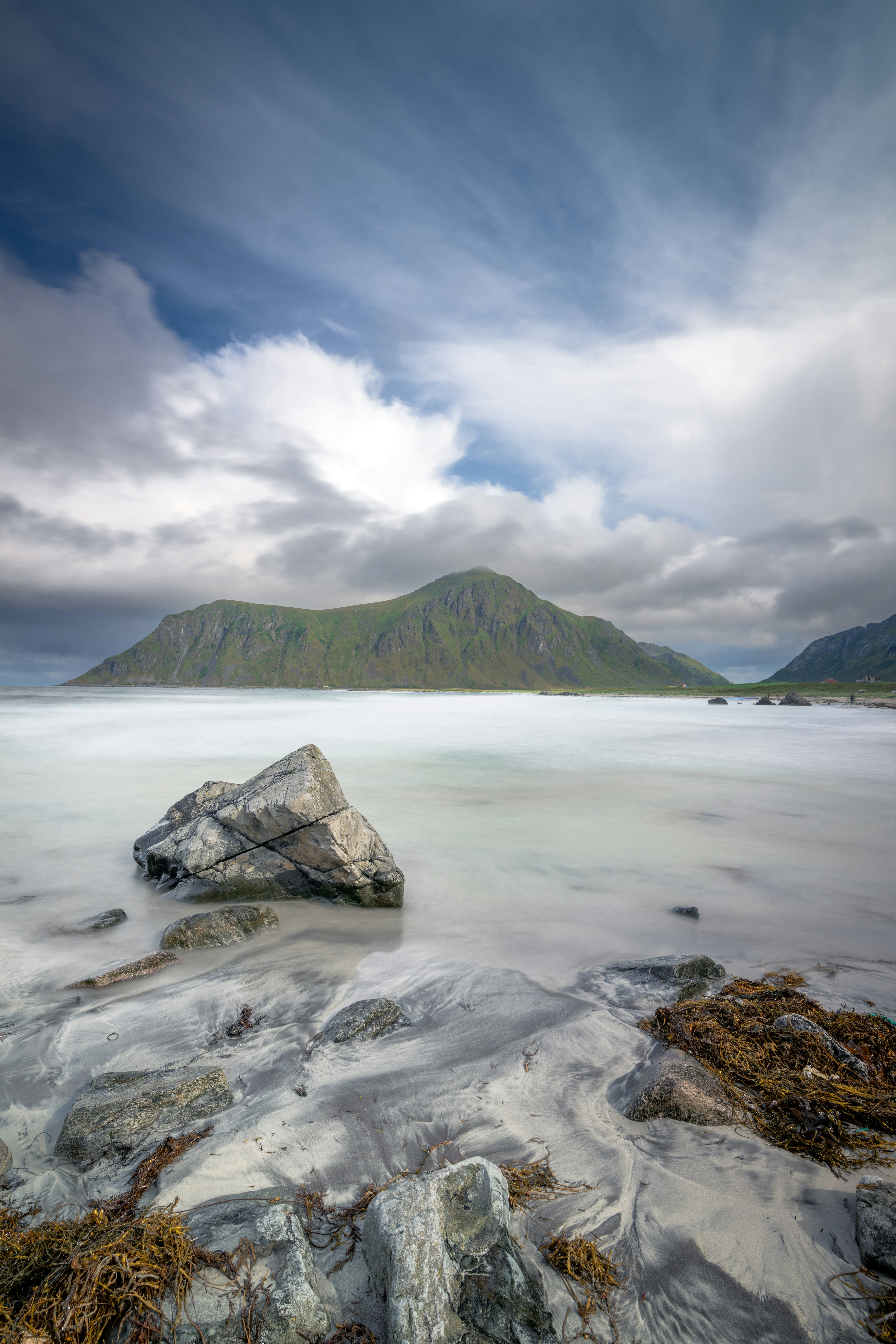 Paisaje montañoso con playa rocosa y cielo nublado