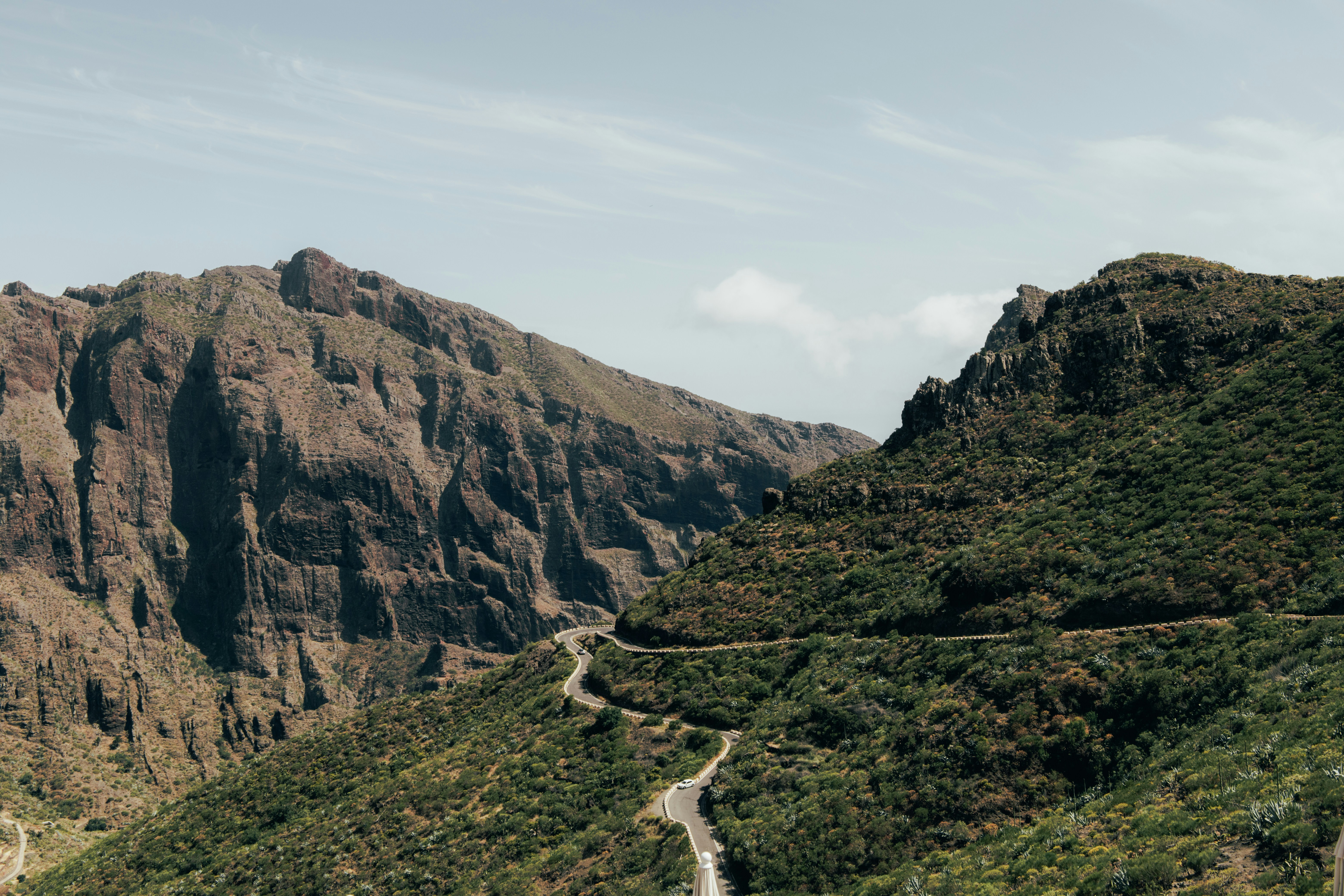 Strada tortuosa attraverso montagne verdi e rigogliose sotto un cielo nuvoloso
