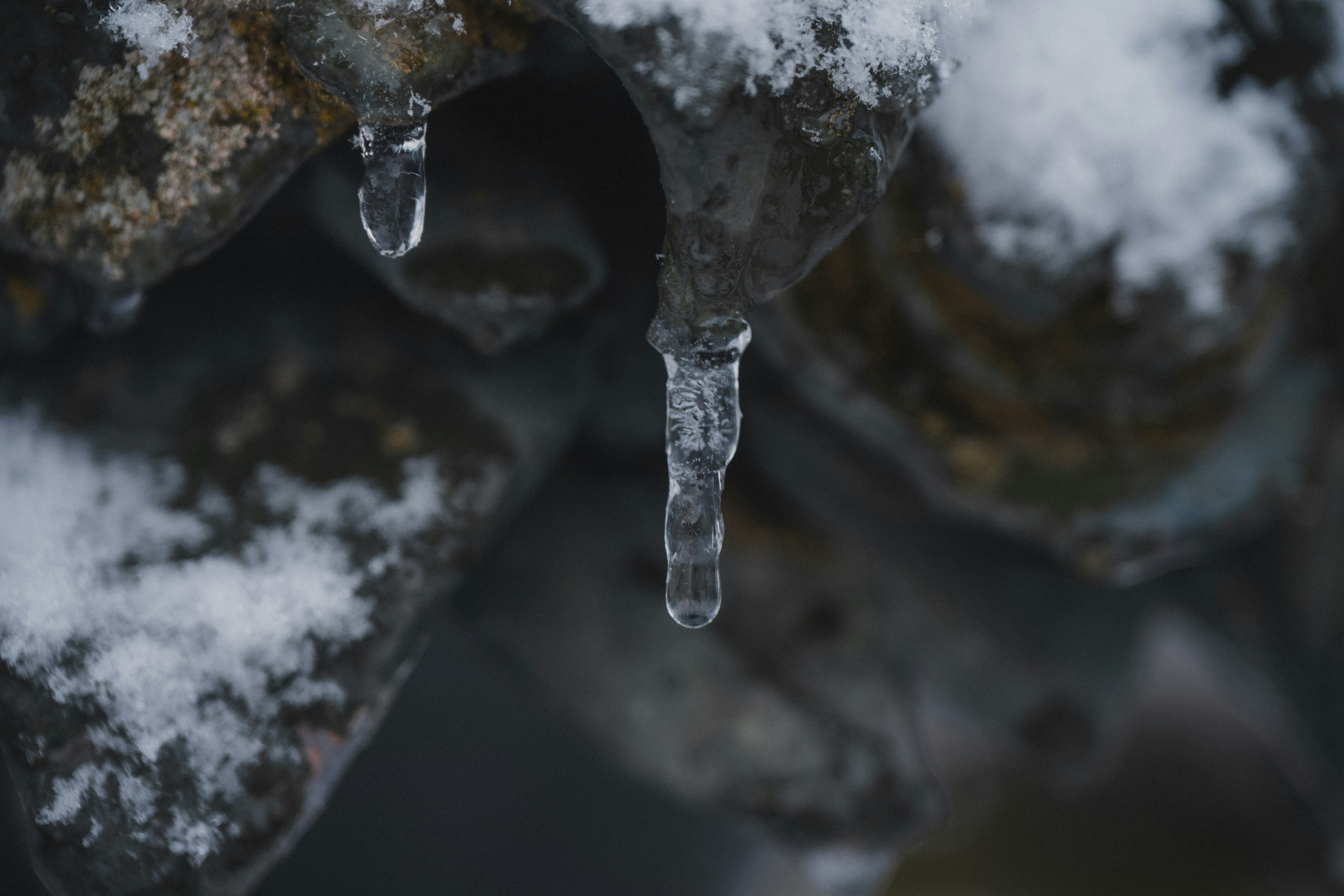 Melting icicles hang from a snow-covered roof.