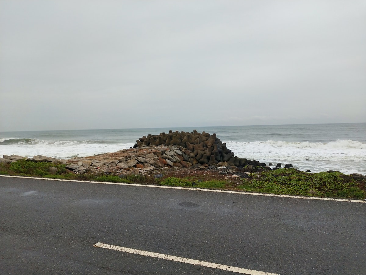 Rocky shore with ocean waves crashing against dark stone under moody skies