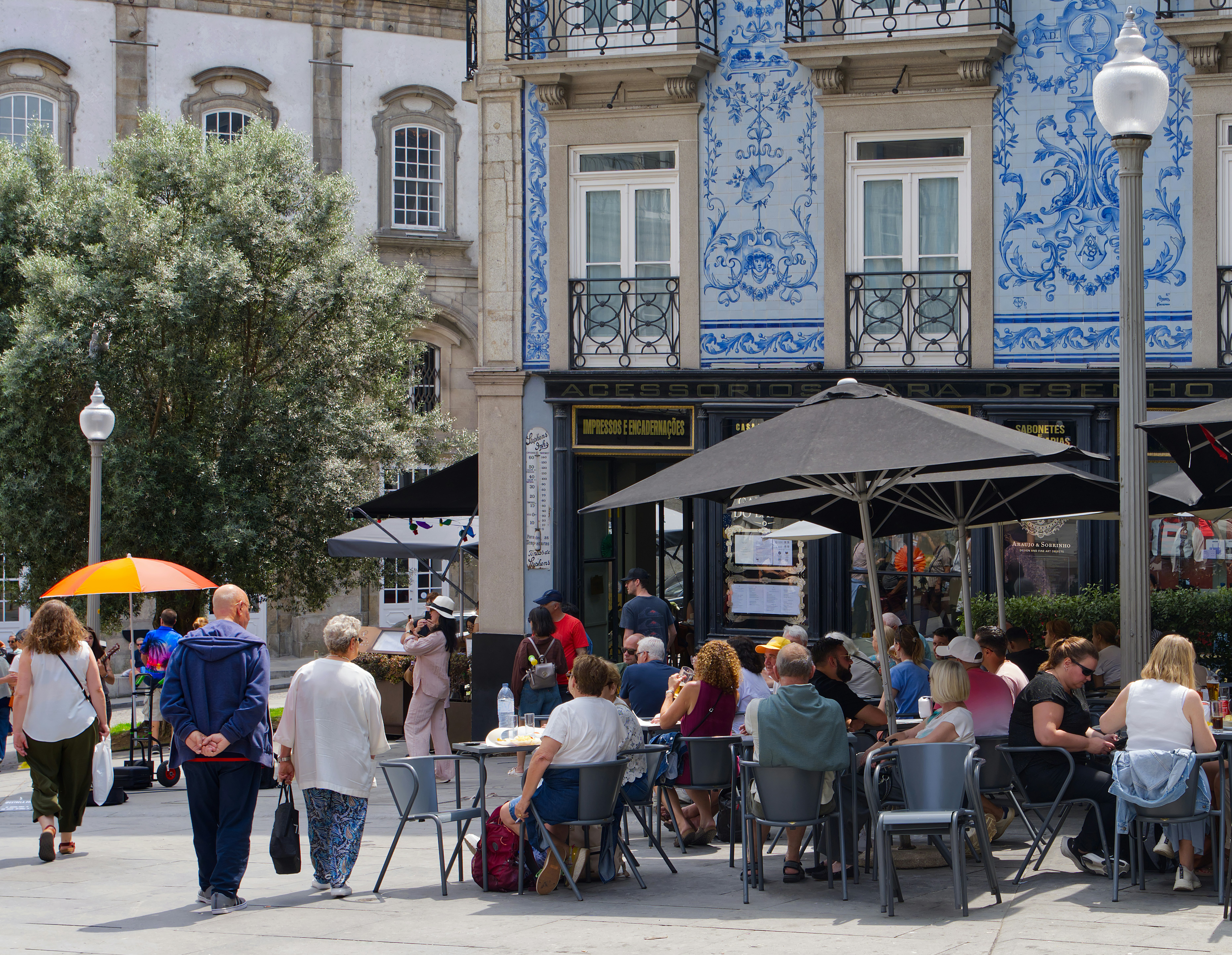 Pessoas jantarem em um café ao ar livre com prédio de azulejos