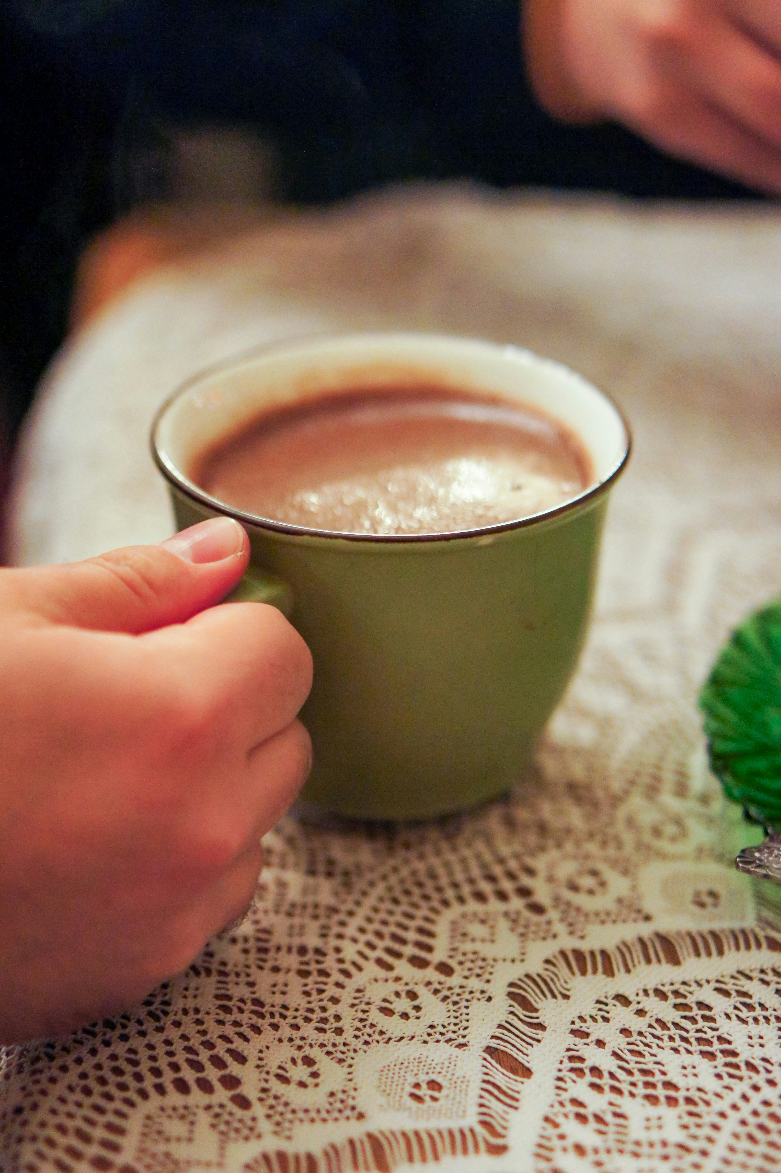 A hand holding a mug of hot chocolate