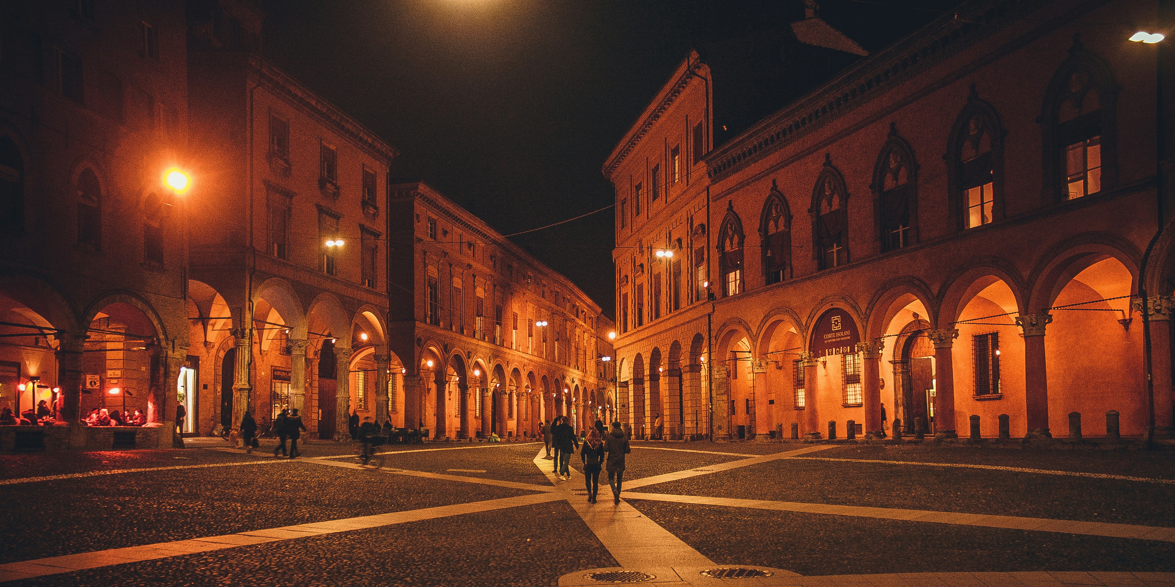 Arched buildings line a cobblestone square at night.